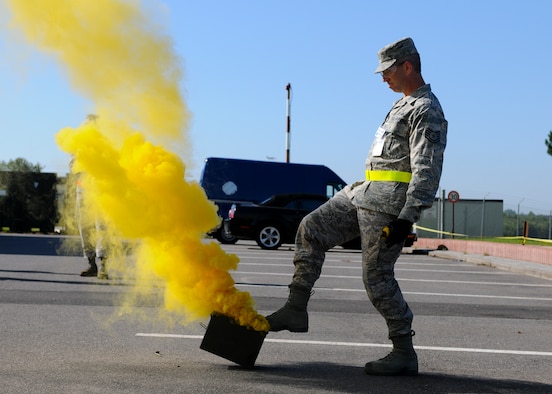 SPANGDAHLEM AIR BASE, Germany -- Tech Sgt. Jeffrey Morman, 52nd Maintenance Group exercise evaluation team, releases yellow smoke to simulate an indirect fire attack in the parking lot of the 81st Fighter Squadron Aug. 4. The smoke was used as a visual indicator of an explosion for nearby players in the 52 FW’s Phase II exercise here. This Phase II is the first of five total exercises to prepare the 52nd Fighter Wing for a NATO Tactical Evaluation in June 2010. (U.S. Air Force photo/Airman 1st Class Nathanael Callon)