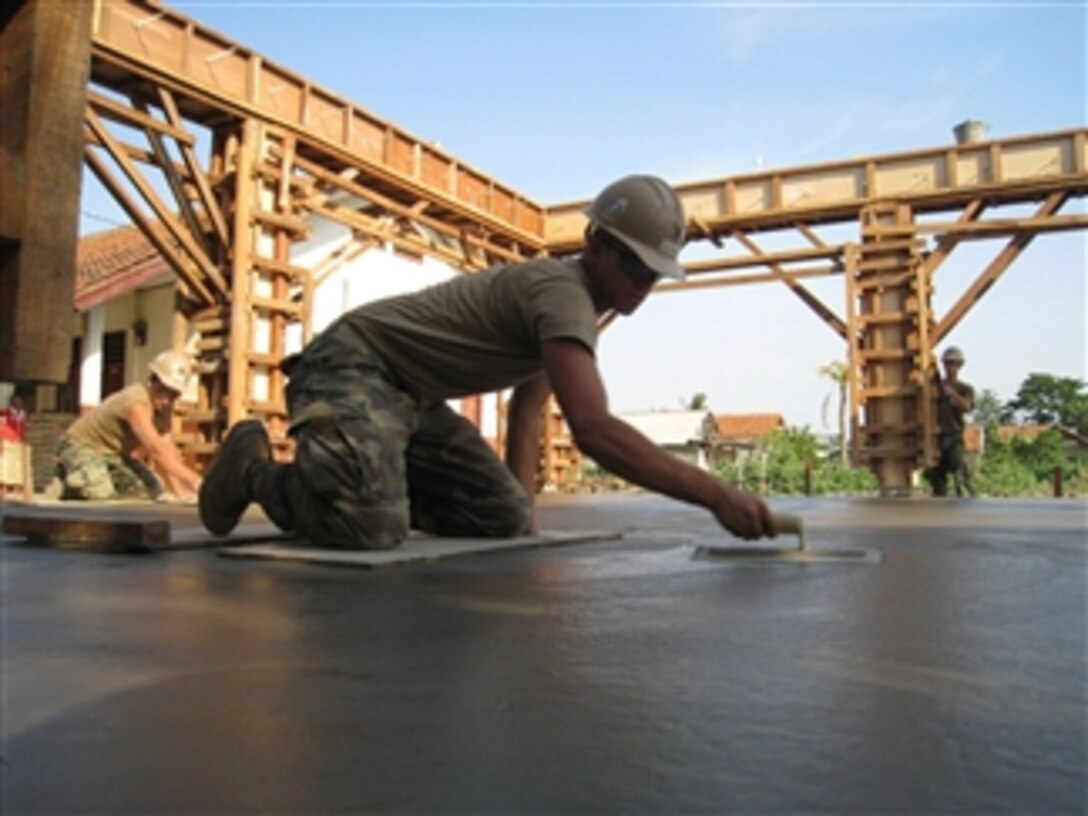 U.S. Navy Petty Officer 2nd Class Eric George, assigned to Naval Mobile Construction Battalion 40, uses a trowel to smooth out a concrete building slab for a new multiuse building at Pusaka Rakyat Primary School in Bekasi, Indonesia, during the first phase of Cooperation Afloat Readiness and Training Indonesia 2009 on July 29, 2009.  Cooperation Afloat Readiness and Training is a series of bilateral exercises held annually in Southeast Asia to strengthen relationships and enhance the operational readiness of the participating forces.  