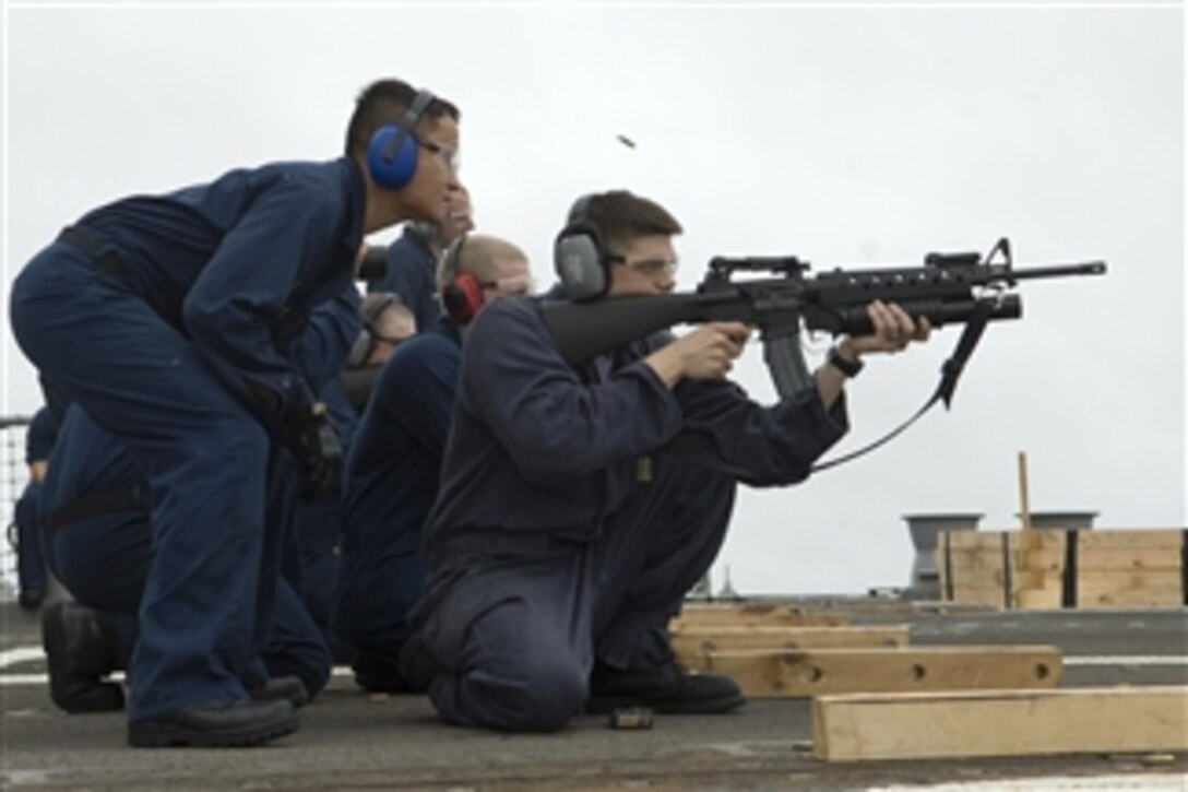 U.S. Navy Petty Officer 2nd Class Chaung Pha observes as Petty Officer 2nd Class Donipaul Briscoe fires an M-16 rifle during small arms firing aboard the guided-missile destroyer USS McCampbell (DDG 85) while underway in the Pacific Ocean on Aug. 3, 2009.  