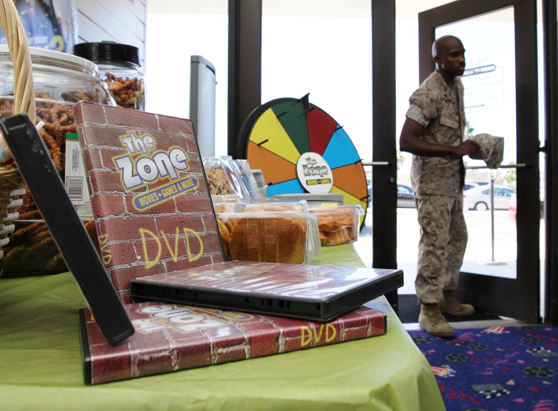 Cpl. Shawn Hill, radio operator, 1st Air Naval Gunfire Liaison Company, 1st Marine Expeditionary Force, walks into Marine Corps Community Services' The Zone during the grand reopening at Pacific Plaza, Aug. 7.  The new 1,800 square foot location now offers every movie for 99 cents and has a larger video game collection. ::r::::n::::r::::n::