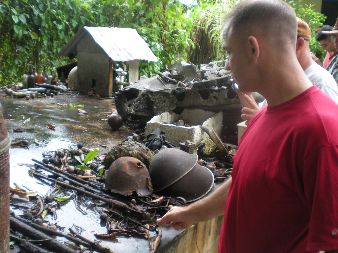 Marine Capt. Raymond J. Scott, Headquarters and Headquarters Squadron Marine Transport Squadron::r::::n::Detachment officer in charge and aircraft safety officer, looks on with other Marines at the remanants of a battle on Tawara Aug. 7 as part of their island-hop trip. Three Marines won seats aboard the C-12 that carried them to the islands in a competition set forth by Lt. Col. Tray J. Ardese, H&HS commanding officer.