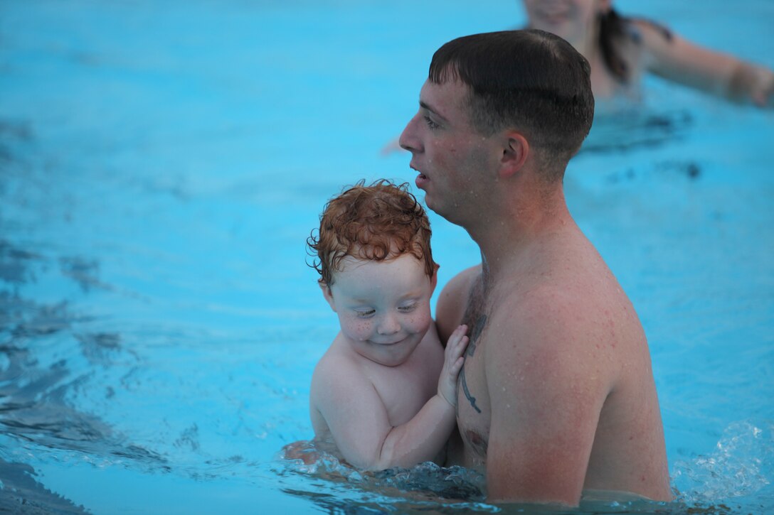 Lance Cpl. Jonathan Jones, a rifleman with Company K, 3rd Battalion, 6th Marine Regiment, takes care of his cousin's son in the pool during the back-to-school pool party held, Aug. 8. The party was a chance for members of the battalion to meet and celebrate before the children went back to school.