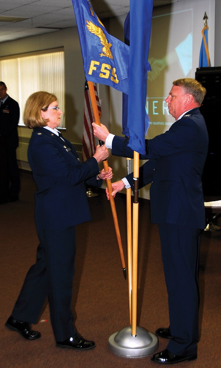 Col. Steven C. Warren, 114th Mission Support Group commander, hands Lt. Col. Tamara D. Mielke, 114th Force Support Squadron commander, the new 114th FSS flag during the stand up ceremony at Joe Foss Field on May 3.(U.S. Air Force Photo by Master Sgt Chris Stewart)