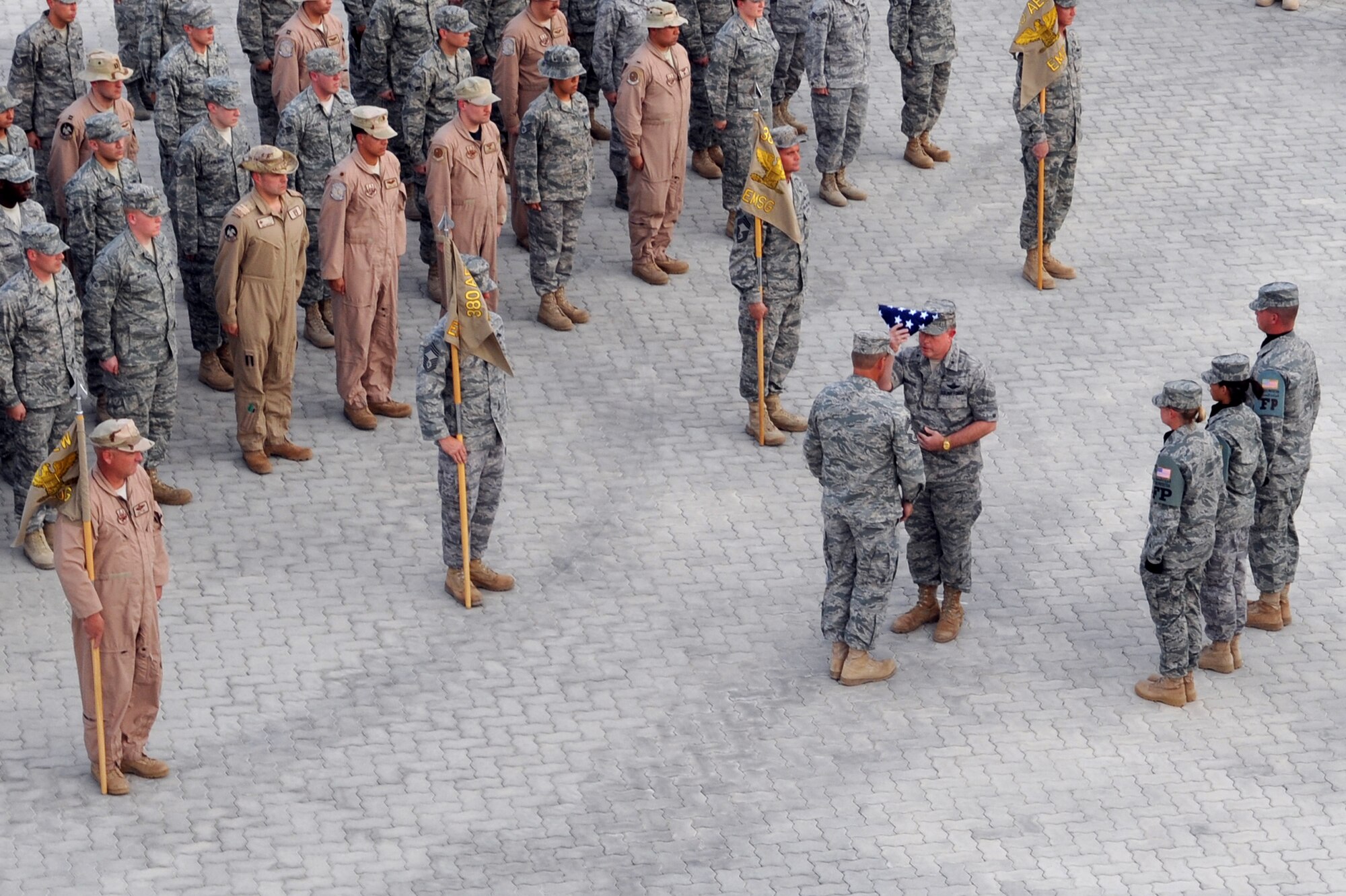 SOUTHWEST ASIA - Brig. Gen. Bryan Benson, 380th Air Expeditionary Wing commander, presents the colors to Chief Master Sgt. Martin Smith, 380th Air Expeditionary Wing command chief master sergeant, during the formal retreat ceremony Aug 7. Chief Smith will soon return to his home station of Minot Air Force base, N.D. (U.S. Air Force photo Tech. Sgt. Charles Larkin Sr.)