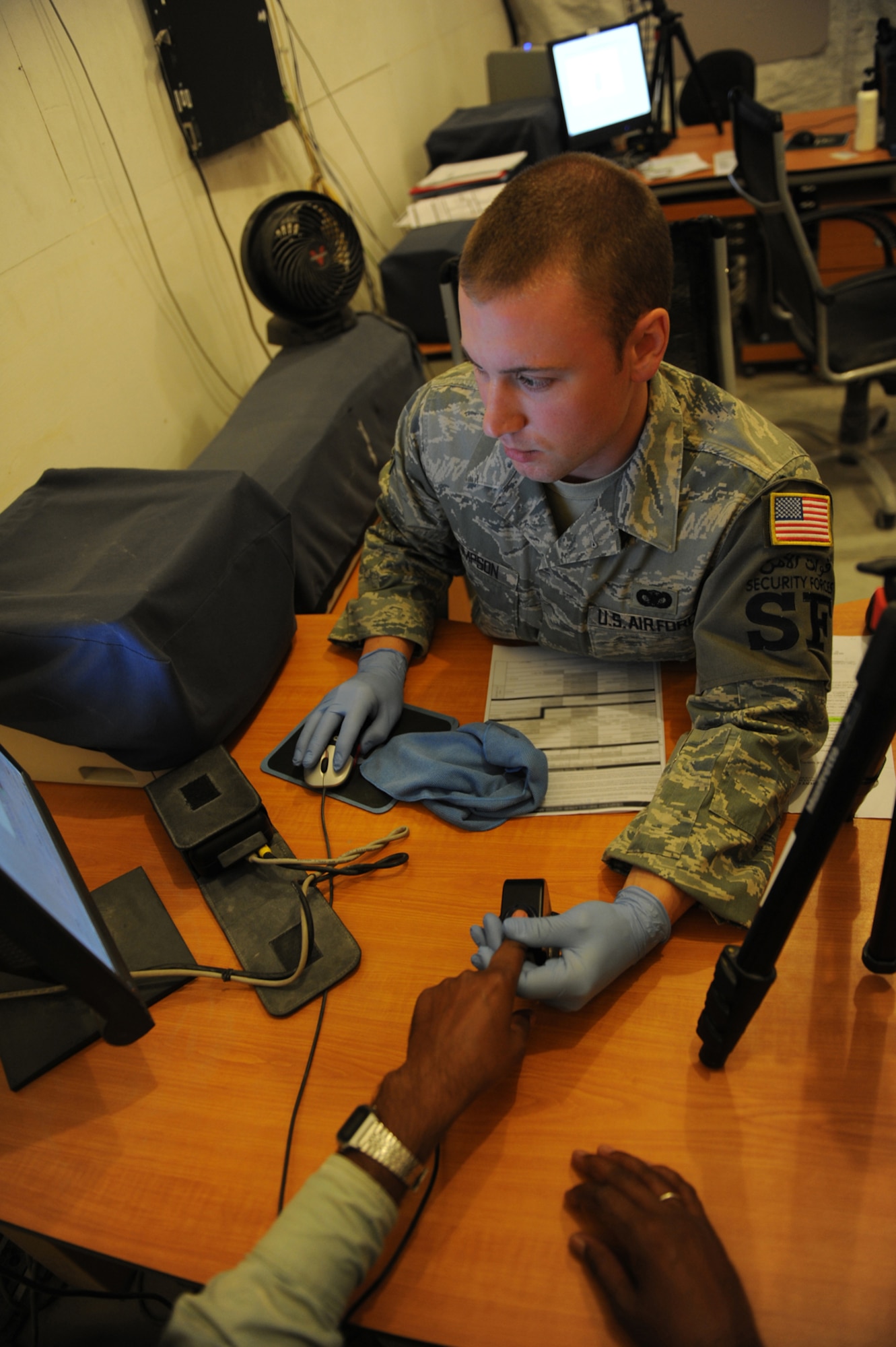Senior Airman Michael Thompson, 379th Expeditionary Security Forces Squadron DBIDS registrar, processes a third country national into the Defense Biometrics
Identification System in Southwest Asia.. DBIDS is an enhanced security system used to monitor entry onto military installations. (US Air Force Photo/Staff Sgt. Robert Barney)