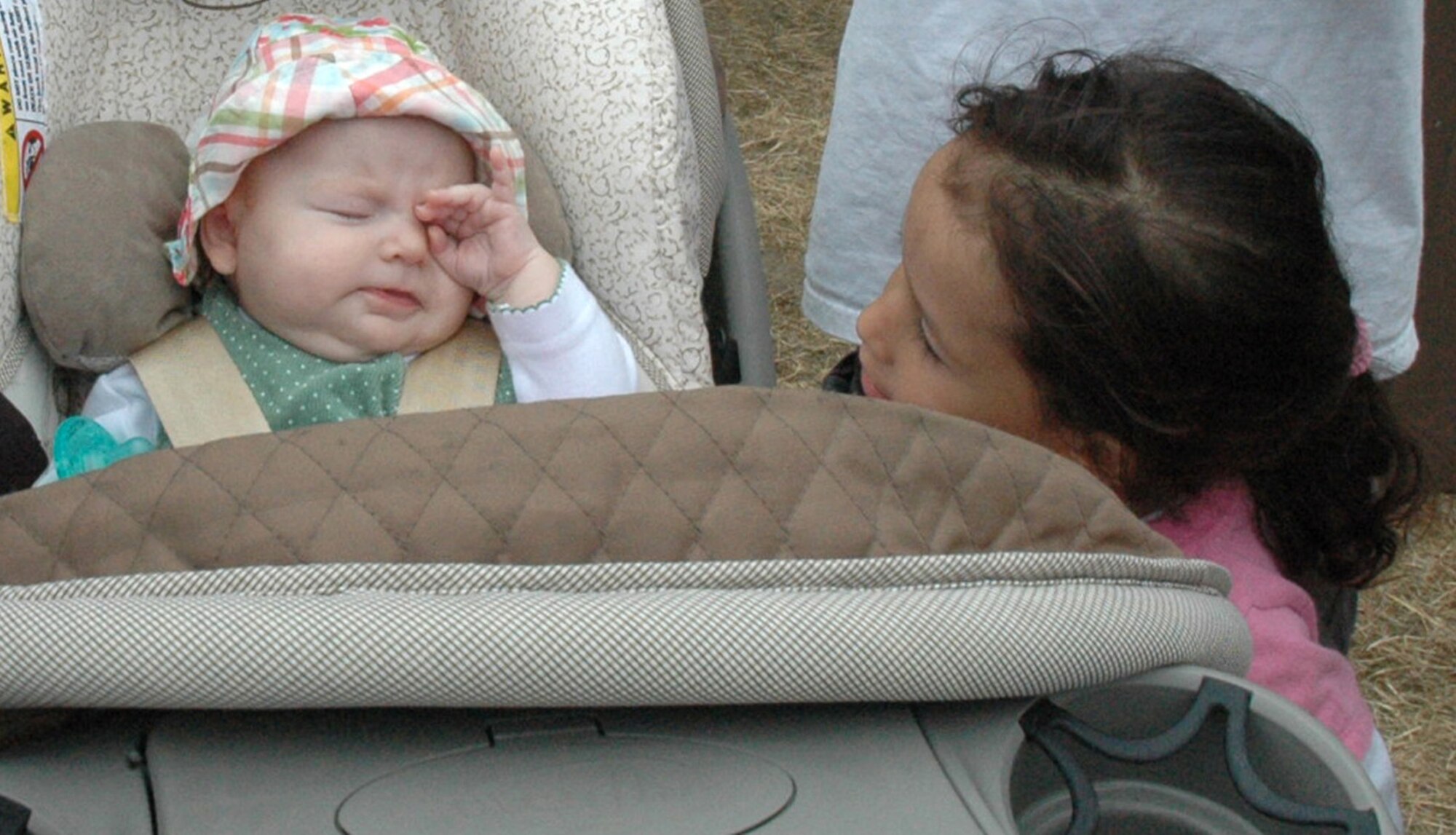 Staff Sgt. Anayansi Chinn's 3-year-old daughter Hope looks intently at Staff Sgt. Patricia Ordway's 3-month-old daughter Elizabeth, who rubs her eyes, while attending the 446th Airlift Wing annual Family Day celebration on Aug. 8, at Heritage Hill, McChord Air Force Base, Wash. Both sergeants work with the 446th Mission Support Squadron here. (U.S. Air Force photo/Tech Sgt. Jake Chappelle).  