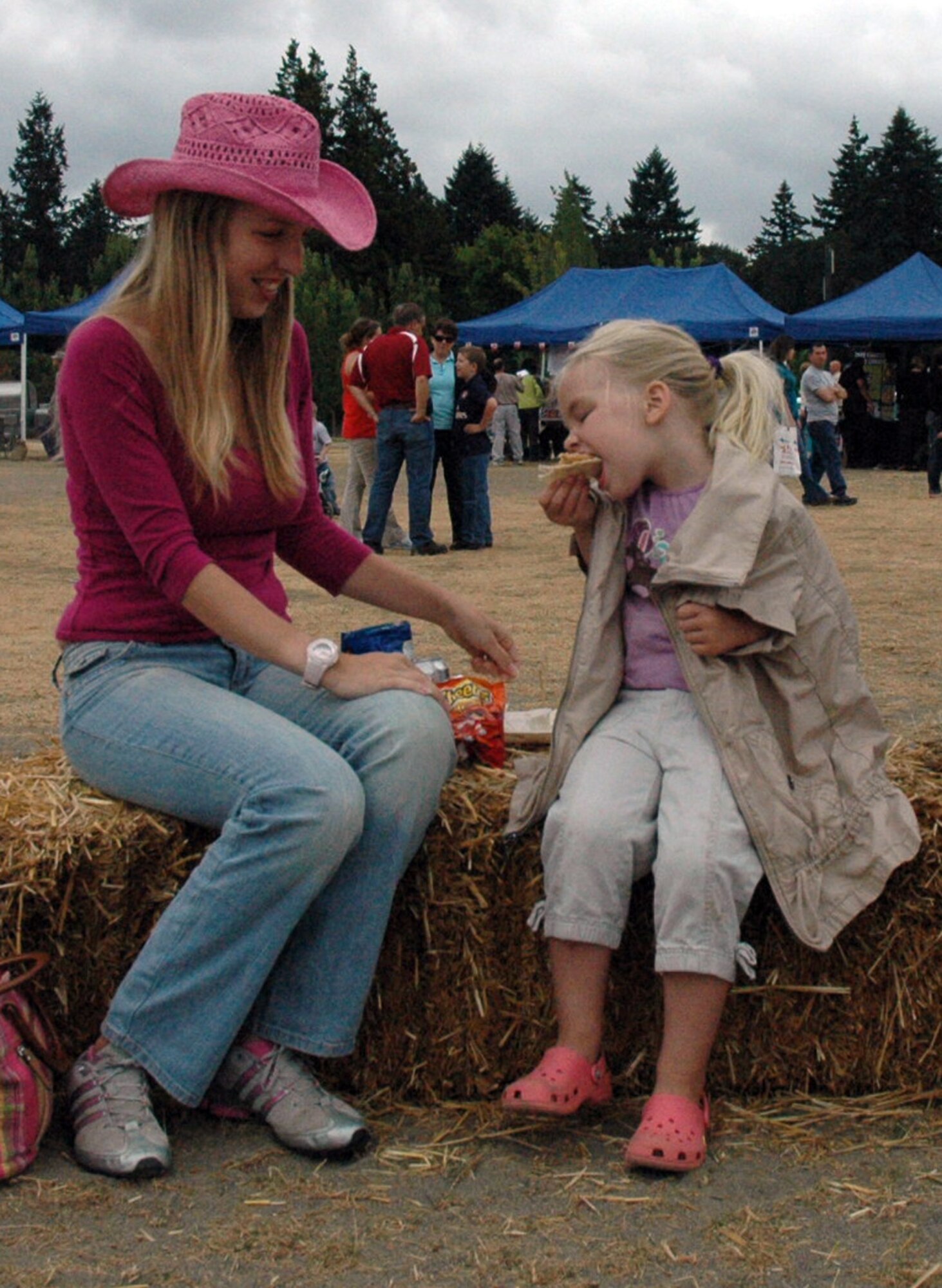 Linnie Nemechek enjoys some snacks with her four-year-old daughter Lily while sitting on a haystack at the 446th Airlift Wing annual Family Day on Aug. 8, at Heritage Hill, McChord Air Force Base, Wash. Linnie's husband, Tech. Sgt. Quentin Nemechek works with the 446th Aircraft Maintenance Squadron. (U.S. Force photo/Tech Sgt. Jake Chappelle).