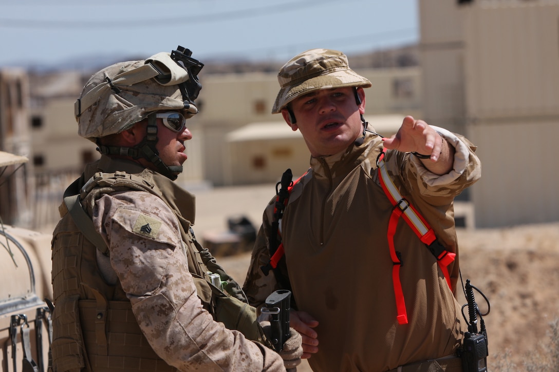 Capt. Richard Sharp, a British Royal Marine with the British Operations Training Advisory Group, lays out a plan of entry to a village with Sgt. Chris Young, an infantry assaultman and vehicle commander with Weapons Company, 3rd Battalion, 24th Marine Regiment, at Combat Center Range 215 Aug. 11.