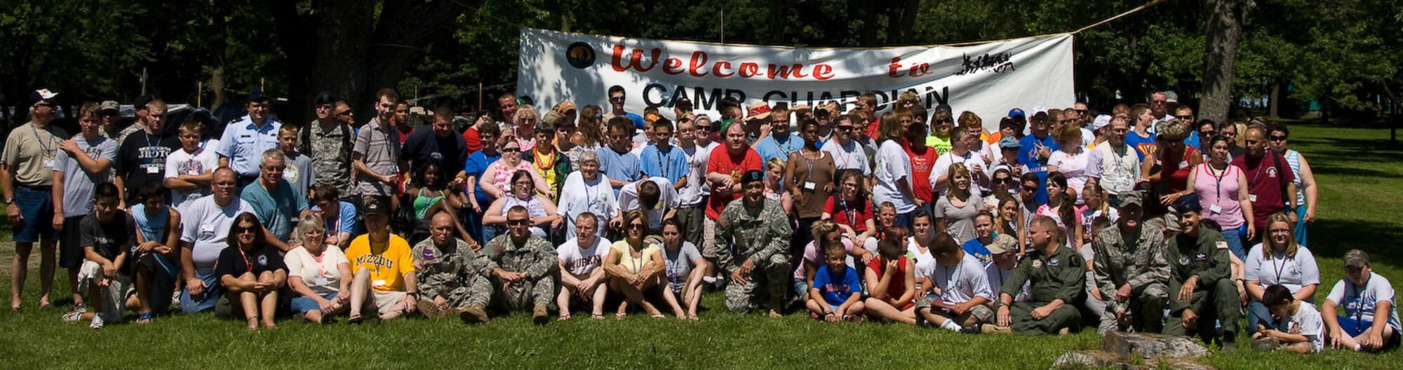 Campers, volunteers and National Guard members pose in front of a large Camp Guardian banner for a group photo during Mo. Adjutant General Stephen Danner's visit to the camp during the 2009 session.