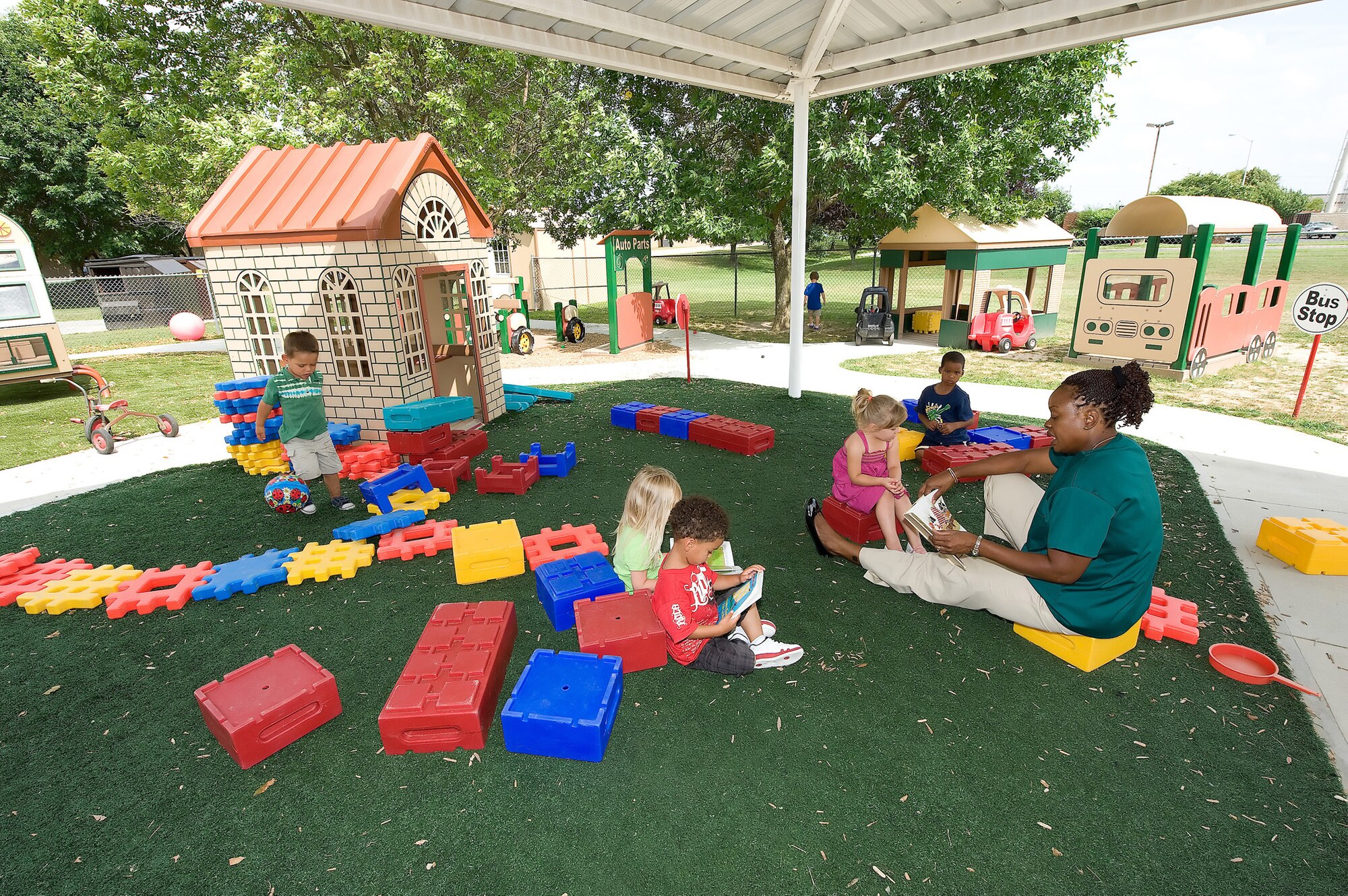 Pat Andries, a provider at the Child Development Center here, reads to preschoolers July 29 during playtime outside. The base CDC recently received accreditation from the National Association for the Education of Young Children, making it one of only two facilities in Kent County, Del., which have earned this level of certification. (U.S. Air Force photo/Jason Minto)