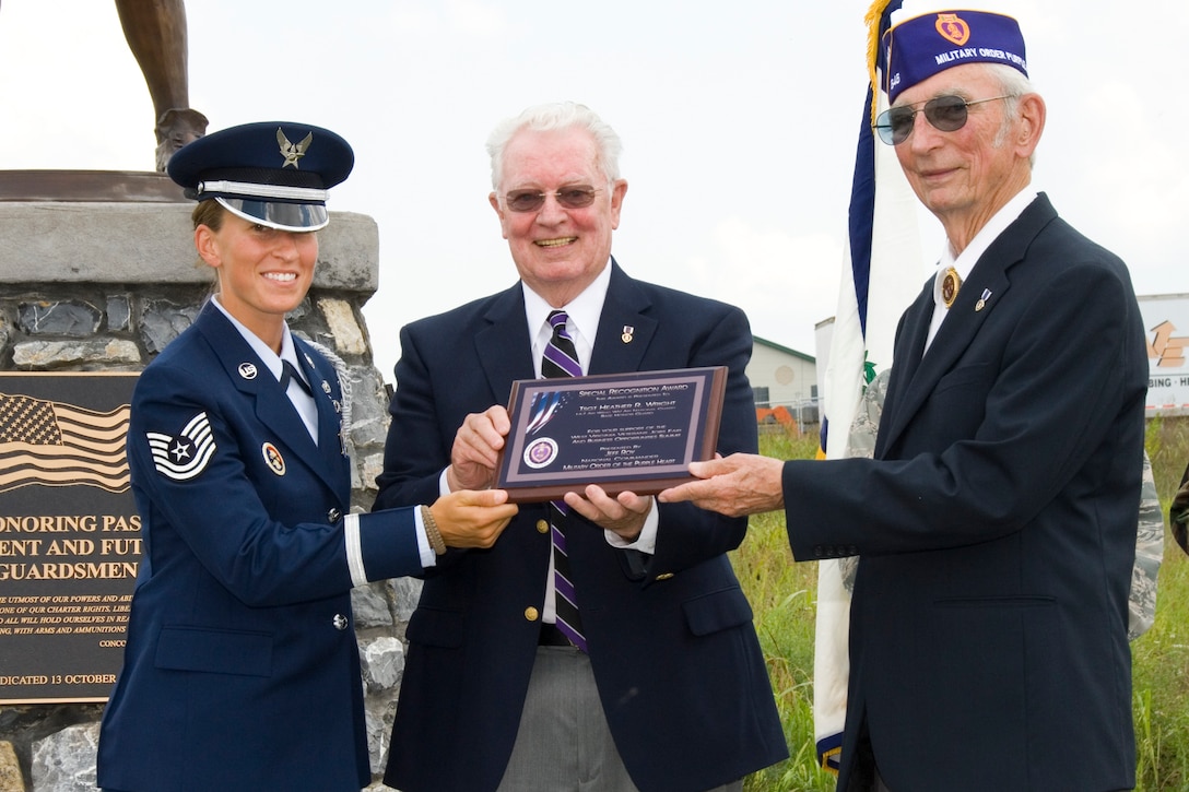 167th Airlift Wing Base Honor Guard member, Technical Sergeant Heather Wright is presented with a plaque of appreciation by Cy Kammeier, Commander of Chapter 646, Military Order of the Purple Heart, and Richard Seeley, Department Commander WV, Military Order of the Purple Heart, during a ceremony at the 167th Airlift Wing on August 1, 2009. Wright and three other members of the base honor guard team were presented the plaques of appreciation for their participation in a job fair and business opportunities summit held at the Martinsburg Veterans Administration Medical Center in June. (U.S> Air Force photo by Master Sgt Emily Beightol-Deyerle)