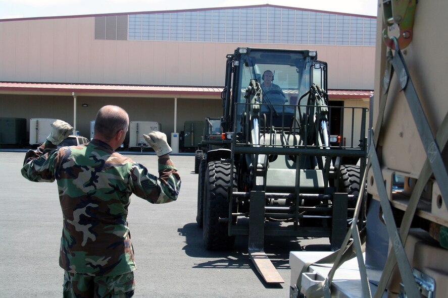 Tech. Sgt. Tim Naquin, air transportation craftsman for the 573rd Global Support Squadron at Travis Air Force Base, Calif., provides guidance to Tech. Sgt. John Fetter, also an air transportation craftsman, as Sergeant Fetter drives an all-terrain forklift into position to move a pallet at the unit's deployment warehouse Aug. 6, 2009.  The 573rd GSS is part of the 615th Contingency Response Wing at Travis AFB.  CRWs are Air Mobility Command's quick reaction force for humanitarian relief missions and for opening air bases any where in the world.  (U.S. Air Force Photo/Tech. Sgt. Scott T. Sturkol)