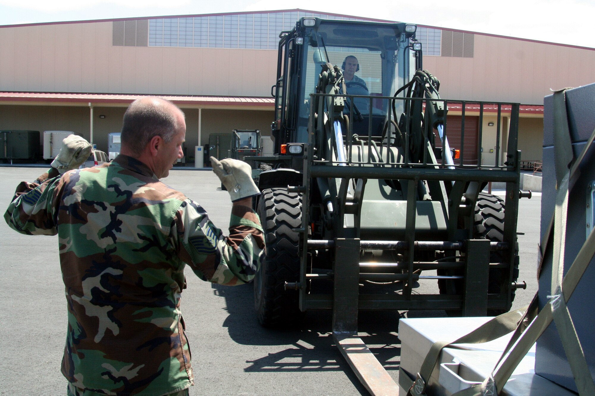 Tech. Sgt. Tim Naquin, air transportation craftsman for the 573rd Global Support Squadron at Travis Air Force Base, Calif., provides guidance to Tech. Sgt. John Fetter, also an air transportation craftsman, as Sergeant Fetter drives an all-terrain forklift into position to move a pallet at the unit's deployment warehouse Aug. 6, 2009.  The 573rd GSS is part of the 615th Contingency Response Wing at Travis AFB.  CRWs are Air Mobility Command's quick reaction force for humanitarian relief missions and for opening air bases any where in the world.  (U.S. Air Force Photo/Tech. Sgt. Scott T. Sturkol)