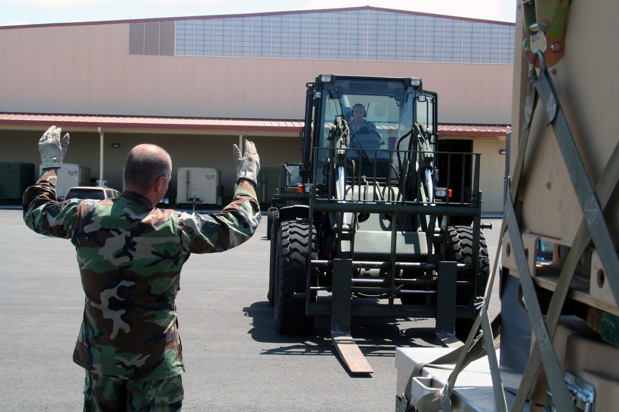 Tech. Sgt. Tim Naquin, air transportation craftsman for the 573rd Global Support Squadron at Travis Air Force Base, Calif., provides guidance to Tech. Sgt. John Fetter, also an air transportation craftsman, as Sergeant Fetter drives an all-terrain forklift into position to move a pallet at the unit's deployment warehouse Aug. 6, 2009.  The 573rd GSS is part of the 615th Contingency Response Wing at Travis AFB.  CRWs are Air Mobility Command's quick reaction force for humanitarian relief missions and for opening air bases any where in the world.  (U.S. Air Force Photo/Tech. Sgt. Scott T. Sturkol)