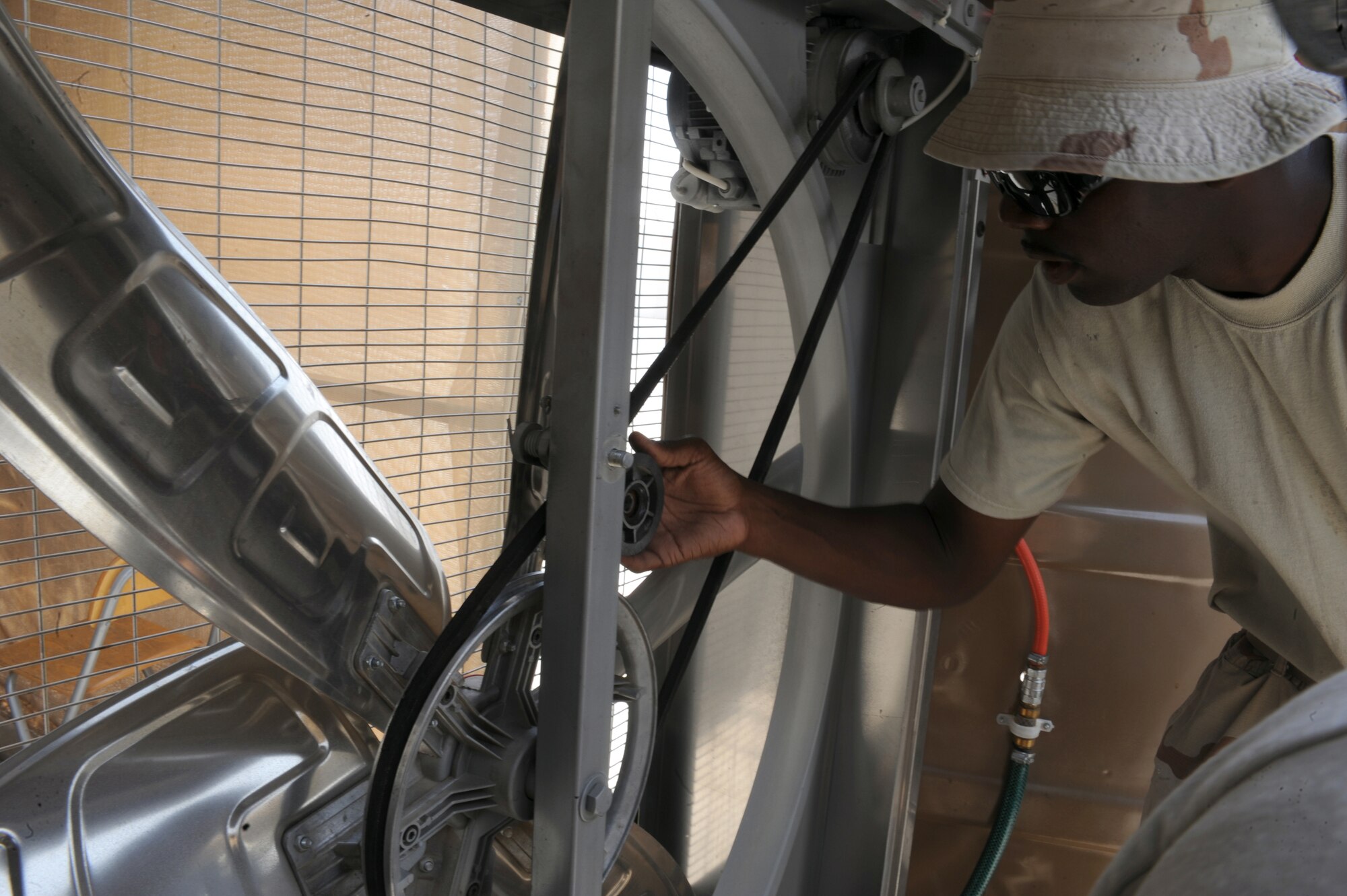 SOUTHWEST ASIA -Airman 1st Class Derrick Glover, 380th Expeditionary Civil Engineer Squadron, replaces the drive belt of a malfunctioning motor driven cooling fan Aug 10. Airman Glover, a heating ventilation and air conditioning system journeyman and is deployed from Spangdahlem AB, Germany, and hails from Branchville, S.C. (U.S. Air Force photo/Tech. Sgt. Charles Larkin Sr)