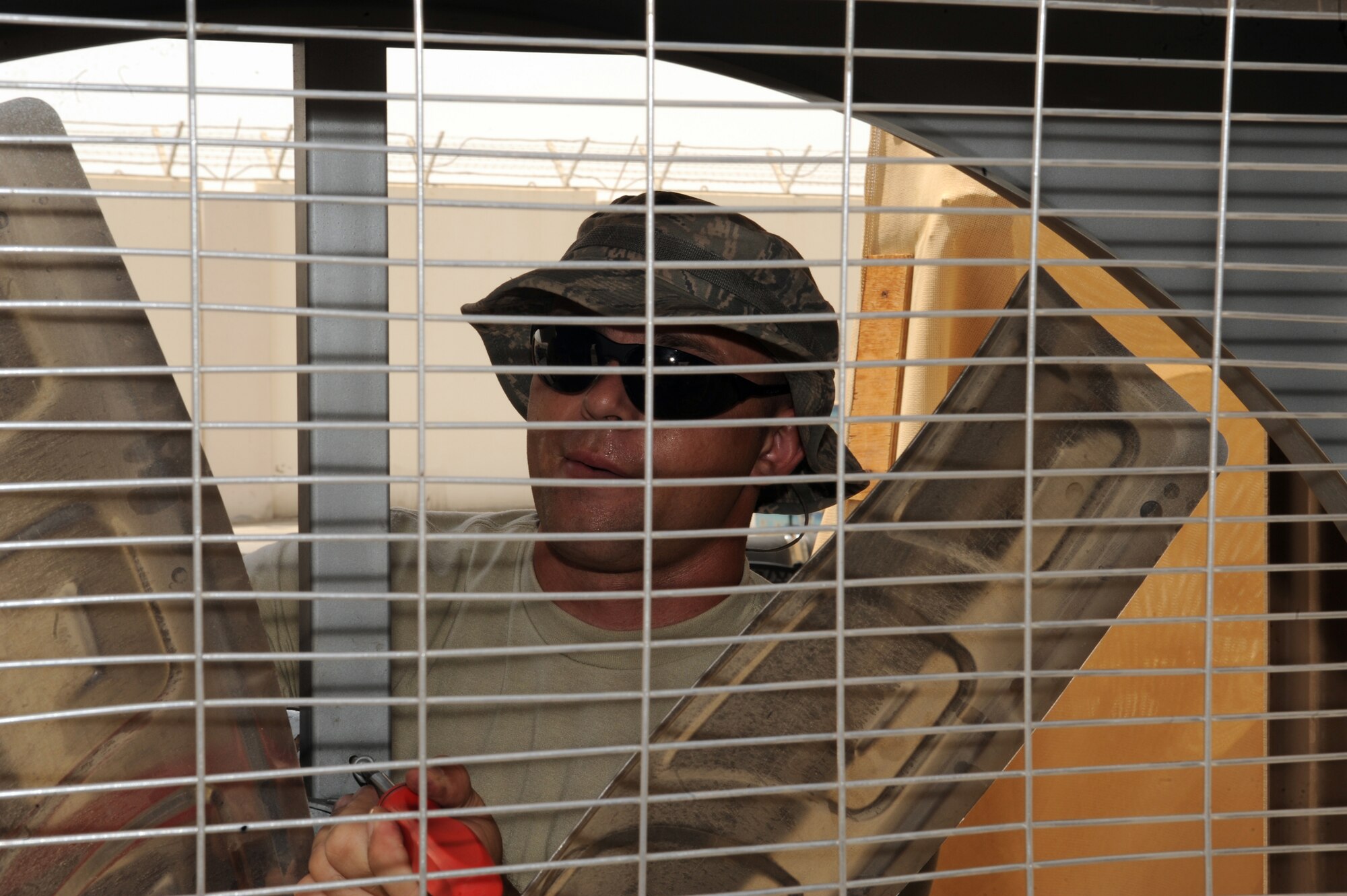 SOUTHWEST ASIA -Senior Airman Nevada Grassie, 380th Expeditionary Civil Engineer Squadron, removes a tension pulley from a motor driven cooling fan Aug 10. Airman Grassie, a heating ventilation and air conditioning system journeyman is deployed from Charleston AFB, S.C. and hails from Ramah, N.M. (U.S. Air Force photo/Tech. Sgt. Charles Larkin Sr)
