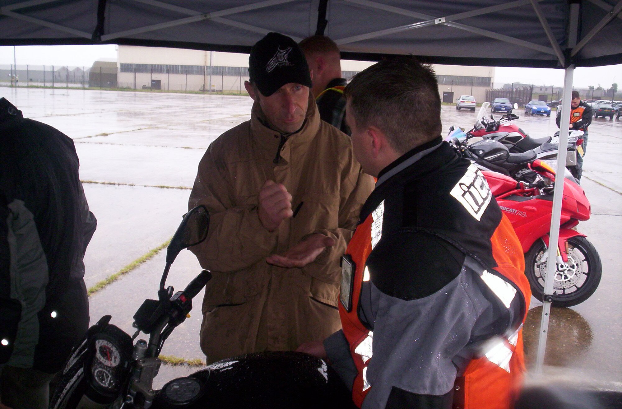 Under cover as rain falls, Andy Ibbot drive home a coaching point with Master Sgt. Wright of the Joint Analysis Center