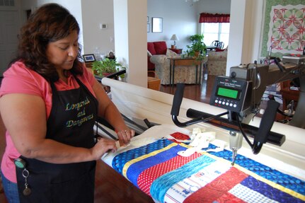 Irene Hafer of Dover, Delaware, checks the edge on a Quilts of Valor quilt in her home studio June 24, 2009. Her apron reads "Longarmed and Dangerous," a reference to the longarm machine she uses to stitch together the three layers of a quilt. (U.S. Air Force photo/Tech. Sgt. Benjamin Matwey)