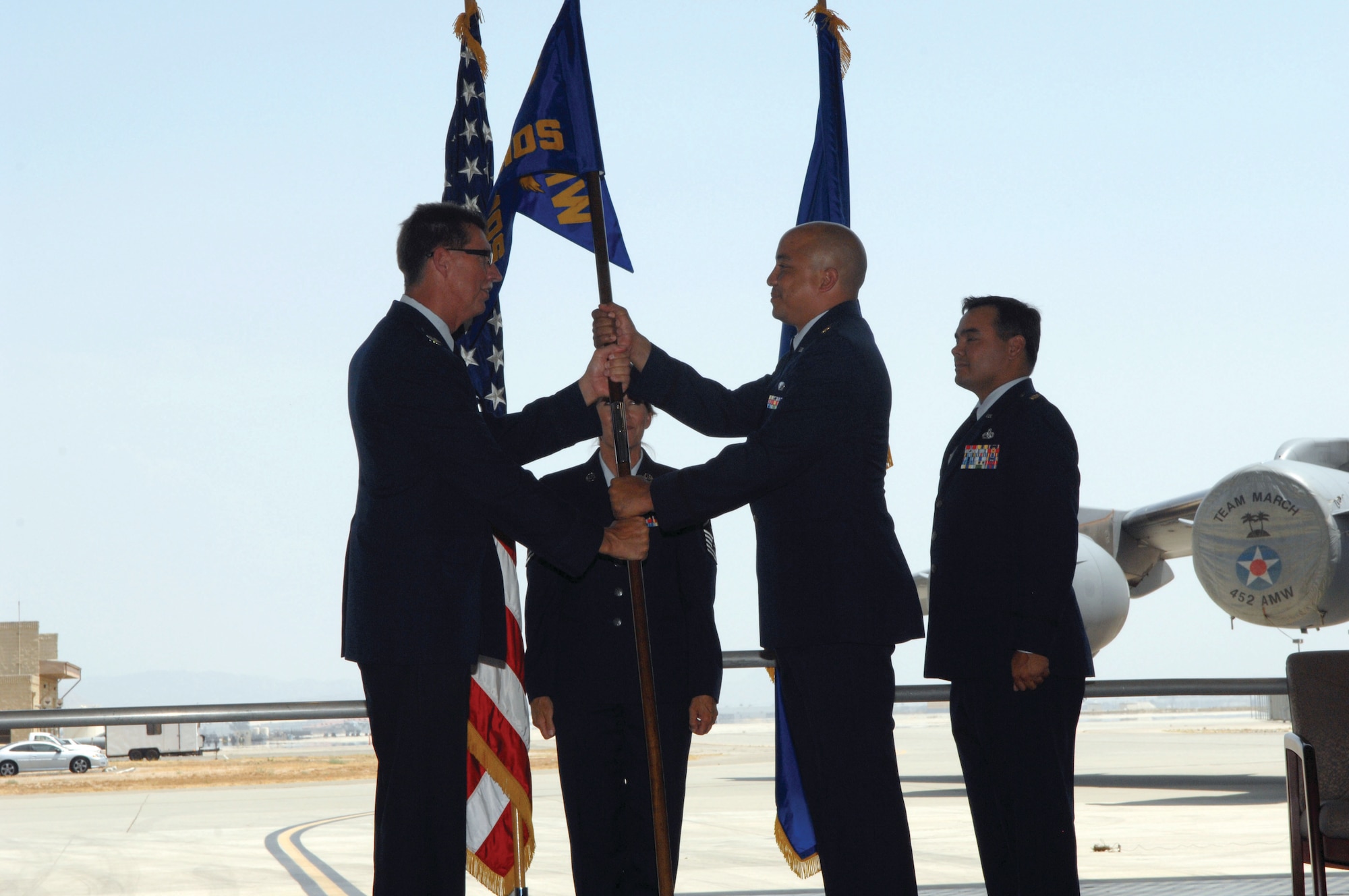 Col. Robert R. Stormes, 452nd Maintenance Group commander, left, passes the guidon to Major William T. Kelley, the new 452nd Maintenance Operations Squadron commander. Major Kevin M. Davis, right, relinquishes command to Major Kelley.  (U.S. Air Force photos by Staff Sgt. Angel Gallardo)