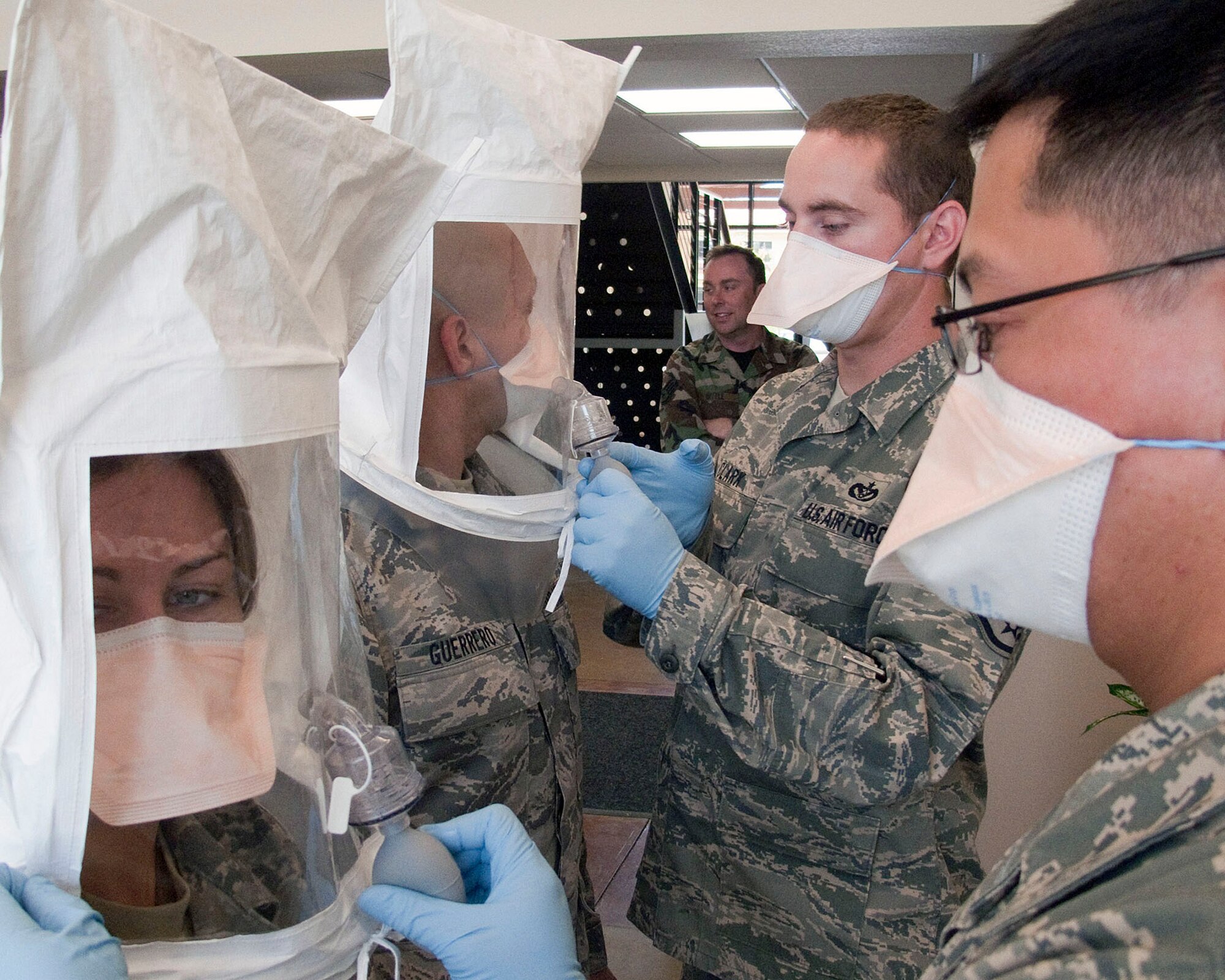 TRAVIS AIR FORCE BASE, Calif. -- Staff Sergeants Richard Giles (far right) and Jason Clark and test the fit of medical facemasks worn by Tech. Sgt. Daniel Guerrero and Staff Sgt. Elle Franz (far left). These disposable respirators help protect health care providers from exposure to airborne, communicable diseases, such as tuberculosis or chickenpox. This routine test introduces airborne particles of a strong yet harmless bittering agent into the air around the mask.  If the wearer doesn’t taste anything awful by the end of the test, the mask is a good fit. Sergeant Clark is a member of the 349th Aerospace Medicine Squadron, bioenvironmental shop; Sergeants Giles, Guerrero and Franz are members of the Aeromedical Staging Squadron. (U.S. Air Force photo / Maj. Robert Couse-Baker) (Released)