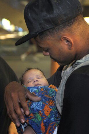 NELLIS AIR FORCE BASE, Nev. - Senior Airman Derrick Acevedo, from the 99th Security Forces Group,  holds his 1-month-old son, Zavien, for the first time. Airman Acevedo was deployed to Kuwait for six months when his son was born. Airman Acevedo and twelve other Nellis security forces Airmen returned home, Aug. 11. (U.S. Air Force photo by Tech. Sgt. Michael R. Holzworth)