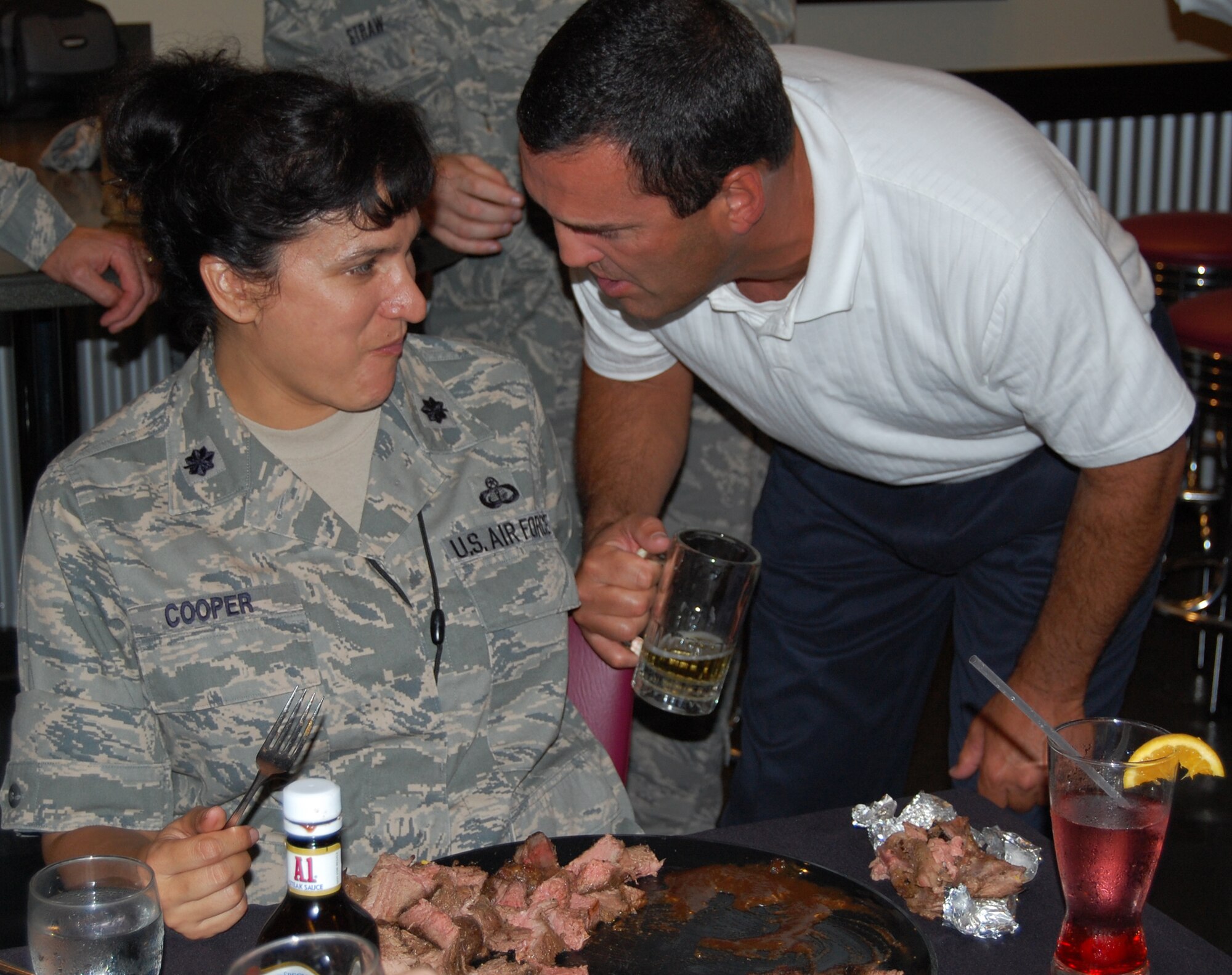 OFFUTT AIR FORCE BASE, Neb. - Lt. Col. Denise Cooper, 55th Force Support Squadron commander, eats another bite of her 96 oz. steak as her husband, Scott, encourages her to keep eating. Contestants who were able to finish the steak, a piece of corn, a baked potato and a side salad were rewarded with $50.