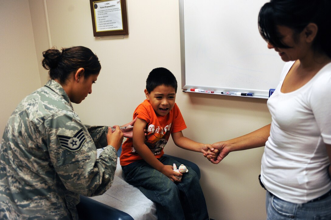 LANGLEY AIR FORCE BASE, Va. -- Staff Sgt Brenda Ayala, 1st Medical Operations Squadron, administers a shot to Isaac Moreno Aug. 8, while his mom, Joanne Moreno, holds his hand. Langley Hospital held a School and Sports Physicals Day to assist parents and children in getting needed immunizations before the start of the school year. (U.S. Air Force photo/Senior Airman Scott Aldridge)