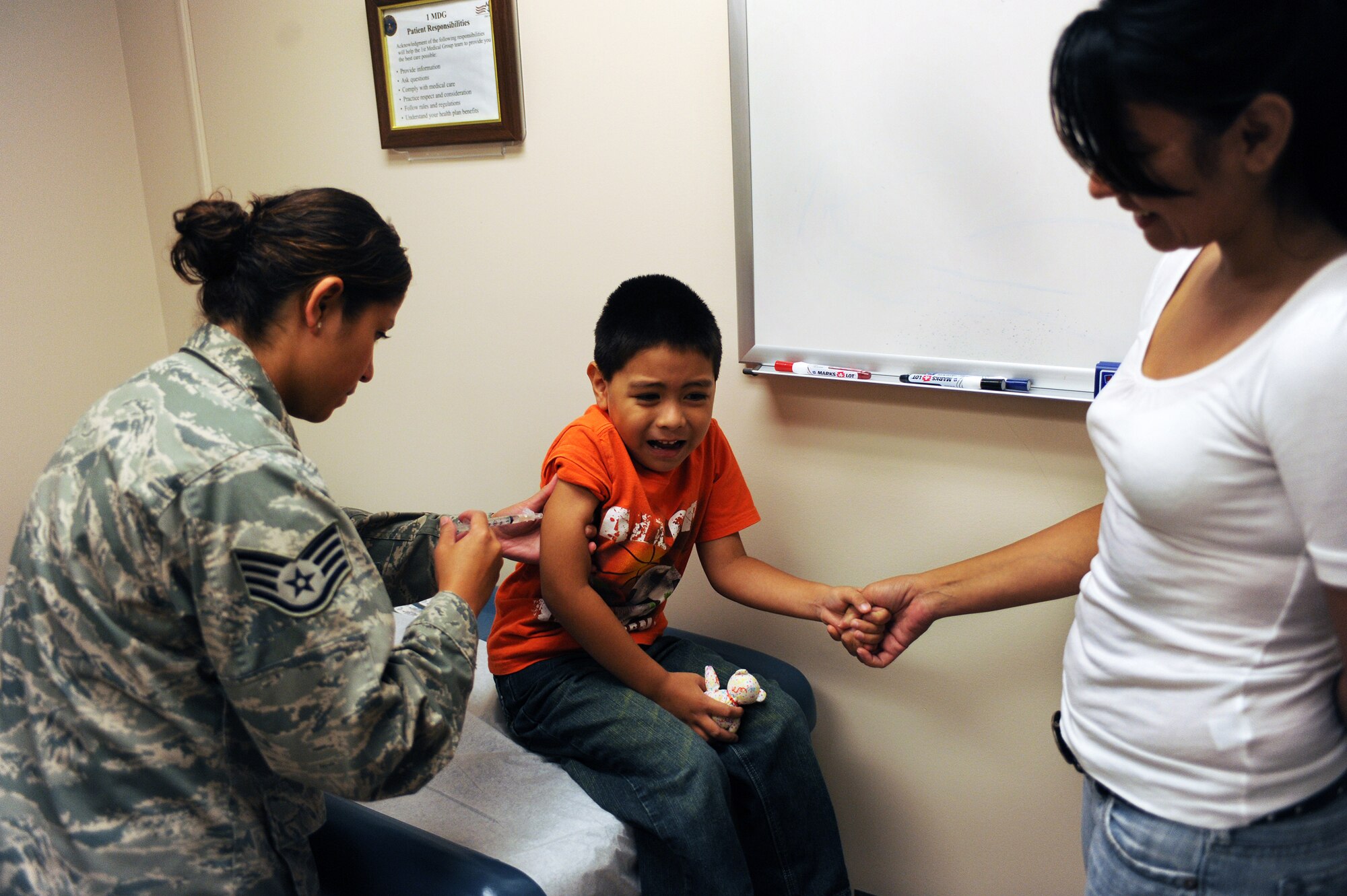 LANGLEY AIR FORCE BASE, Va. -- Staff Sgt Brenda Ayala, 1st Medical Operations Squadron, administers a shot to Isaac Moreno Aug. 8, while his mom, Joanne Moreno, holds his hand. Langley Hospital held a School and Sports Physicals Day to assist parents and children in getting needed immunizations before the start of the school year. (U.S. Air Force photo/Senior Airman Scott Aldridge)