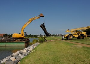 LANGLEY AIR FORCE BASE, Va. -- Contractors unload logs used for the King
Street Pier off a barge and onto the Langley shore Aug. 11. The
storm-battered pier was in existence for more than 75 years until it was
officially closed to the public last September. Demolition of the pier began
recently. (U.S. Air Force photo/Airman Rebecca Montez)