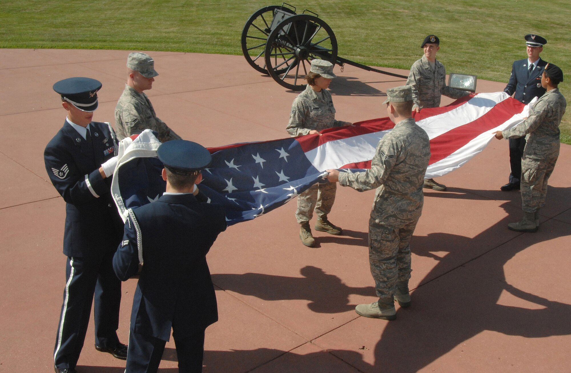 OFFUTT AIR FORCE BASE, Neb.- Offutt Honor Guard members guide Airmen from the Air Force Weather Agency and the 55th Security Force Squadron as they unfold the flag following the retreat ceremony held at the Offutt parade grounds Aug 6.  Offutt's base flag is lowered every Thursday during the ceremony to signal the end of the duty day. Air Force photo by D.P. Heard

