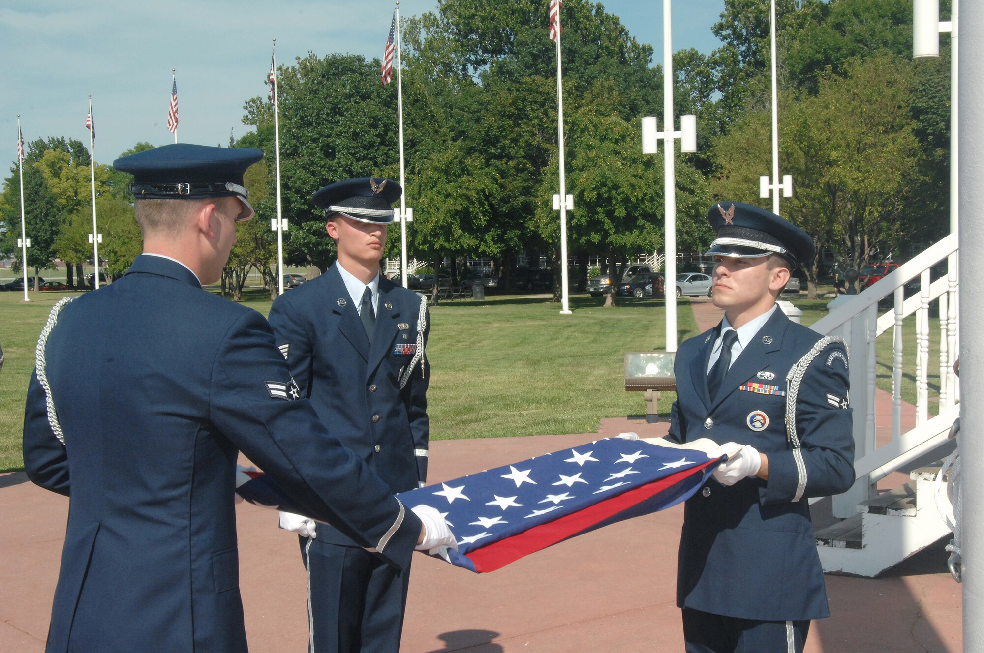 OFFUTT AIR FORCE BASE, Neb.-  Airman 1st Class Raymond Elizalde, an Honor Guard member from the 55th Maintanence Squadron, holds the flag as Airman 1st Class Jeffery Hunsberger, an Honor Guard member from the 1st Aircraft Maintenence Unit, folds it while Staff Sgt. Gene Pabst, non-commissioned officer in charge of the Honor Guard detail from the 97th Intelligence Squadron, watches during the retreat ceremony signaling the end of the duty day at the Offutt Parade Grounds Aug 6. US Air Force photo by D.P. Heard

