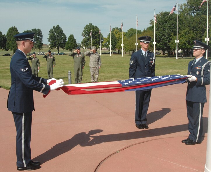 OFFUTT AIR FORCE BASE, Neb.- Airman 1st Class Jeffery Hunsberger, an Honor Guard member from the 1st Aircraft Maintenence Unit, folds the flag that Airman 1st Class Raymond Elizalde, an Honor Guard member from the 55th Maintanence Squadron, while Staff Sgt. Gene Pabst, non-commissioned officer in charge of the Honor Guard detail from the 97th Intelligence Squadron, watches during the retreat ceremony signaling the end of the duty day at the Offutt Parade Grounds Aug 6. Members of the Air Force Weather Agency salute in the background. US Air Force photo by D.P. Heard