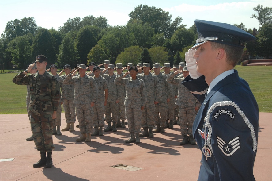 OFFUTT AIR FORCE BASE, Neb.- Staff Sgt. Gene Pabst, non-commissioned officer-in-charge of the Honor Guard detail, salutes the flag with Airmen from the Air Force Weather Agency and 55th Security Forces Squadron during the retreat ceremony signaling the end of the duty day at the Offutt Parade Grounds Aug 6. US Air Force photo by D.P. Heard