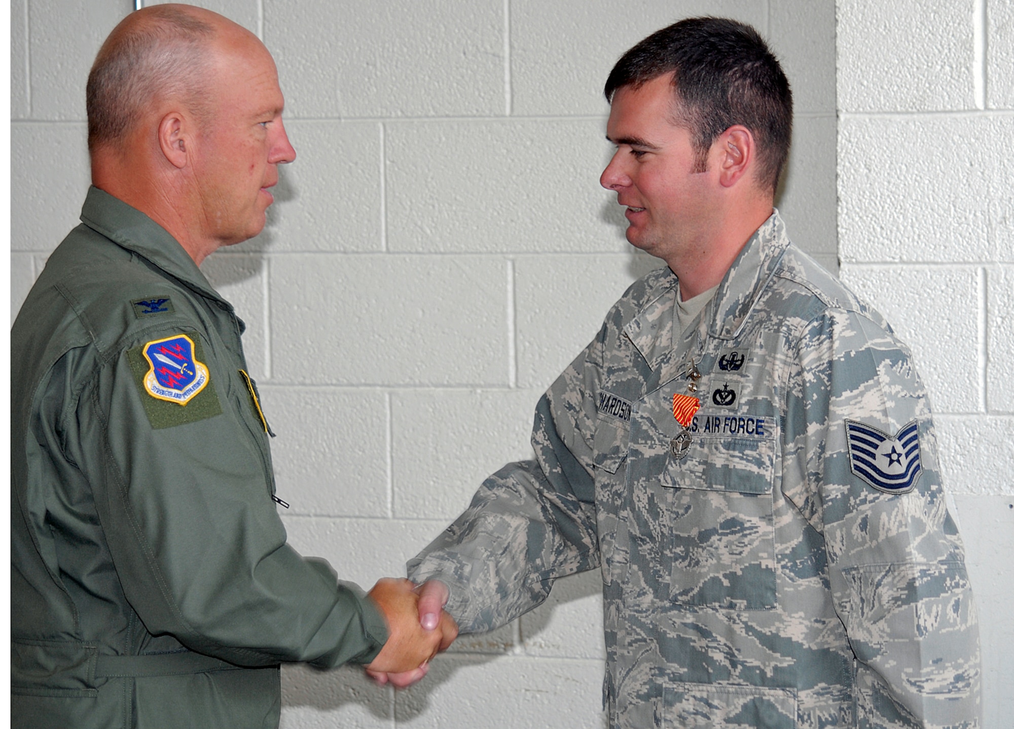 PETERSON AIR FORCE BASE, Colo. -- Col. Jay Raymond, 21st Space Wing commander, presents the Air Force Combat Action Metal to Tech. Sgt. Brandon Richardson, 21st Civil Engineer Squadron, and Senior Airman Grant Schneider, 21st CES Aug. 6. The medal is given to Airmen who have been involved in direct fighting situations where they risked their lives in an enemy engagement. Both Sergeant Richardson and Airman Schneider are explosive ordnance technicians. (U.S. Air Force photo by Larry Hulst).

