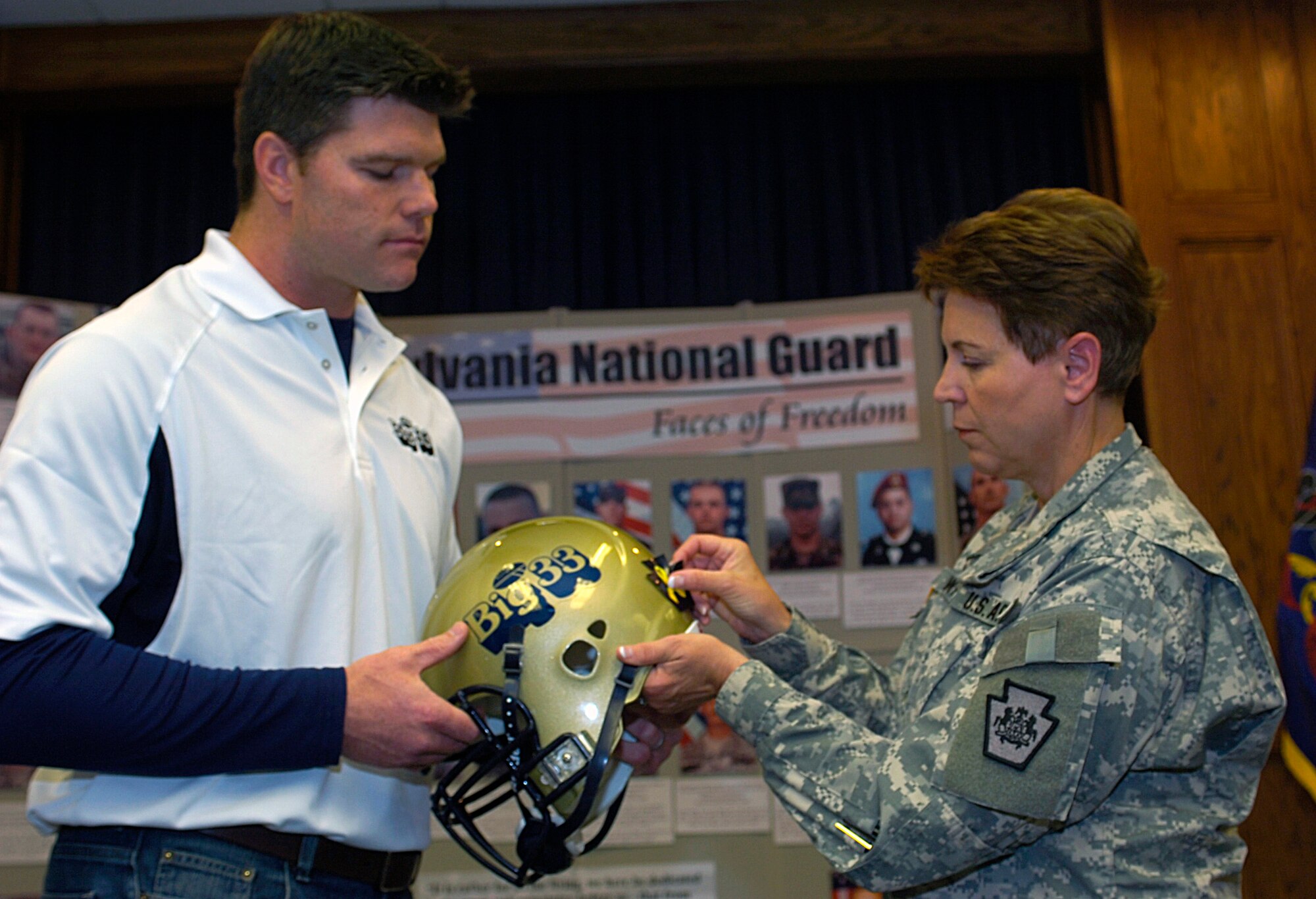 Maj. Gen. Jessica L. Wright, commander of the Pennsylvania National Guard, places the first specially designed helmet sticker with the help of former NFL great and Big 33 honorary chairman Kyle Brady.  Photo by Emily Phillippy.