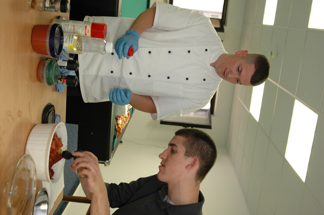 KAPAUN AIR STATION, Germany—Airman 1st Class Scott Shoemaker (right) from the U.S. Forces Police Squadron helps Master Sgt. James Fuller, senior enlisted aide to the U.S. Forces in Europe commander, put ingredients into a chili during a microwave cooking demonstration.  Sponsored by the USAFE command chief’s office, Sergeant Fuller did the demo to help 569th USFPS dorm residents, that have no kitchen facilities, prepare wholesome meals in the microwave. (U.S. Air Force photo by Master Sgt. Corey Clements)
