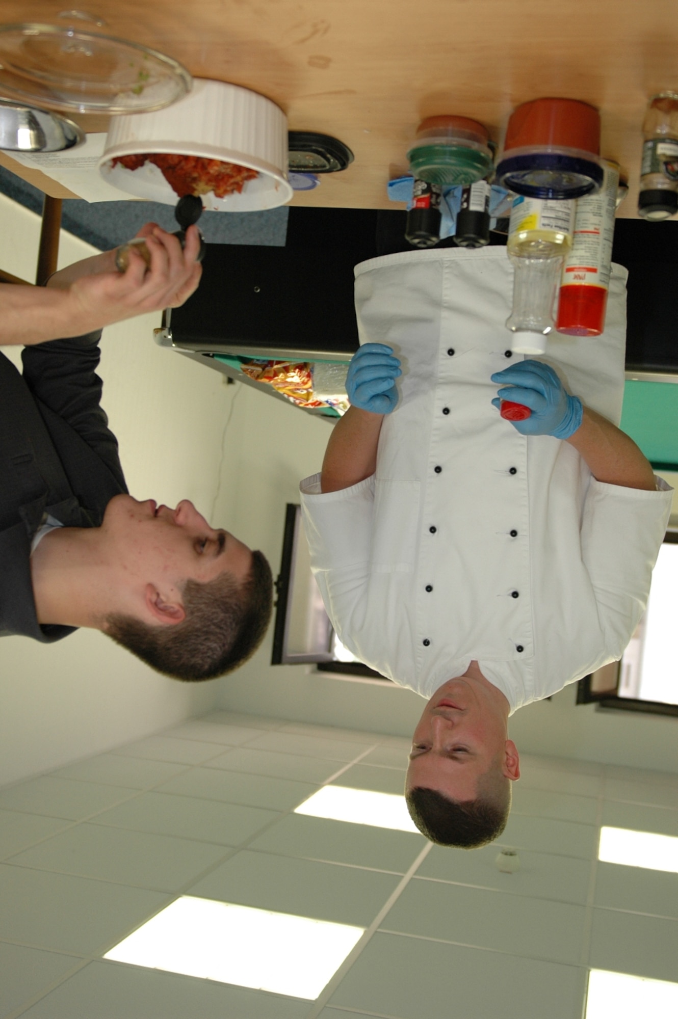 KAPAUN AIR STATION, Germany—Airman 1st Class Scott Shoemaker (right) from the U.S. Forces Police Squadron helps Master Sgt. James Fuller, senior enlisted aide to the U.S. Forces in Europe commander, put ingredients into a chili during a microwave cooking demonstration.  Sponsored by the USAFE command chief’s office, Sergeant Fuller did the demo to help 569th USFPS dorm residents, that have no kitchen facilities, prepare wholesome meals in the microwave. (U.S. Air Force photo by Master Sgt. Corey Clements)