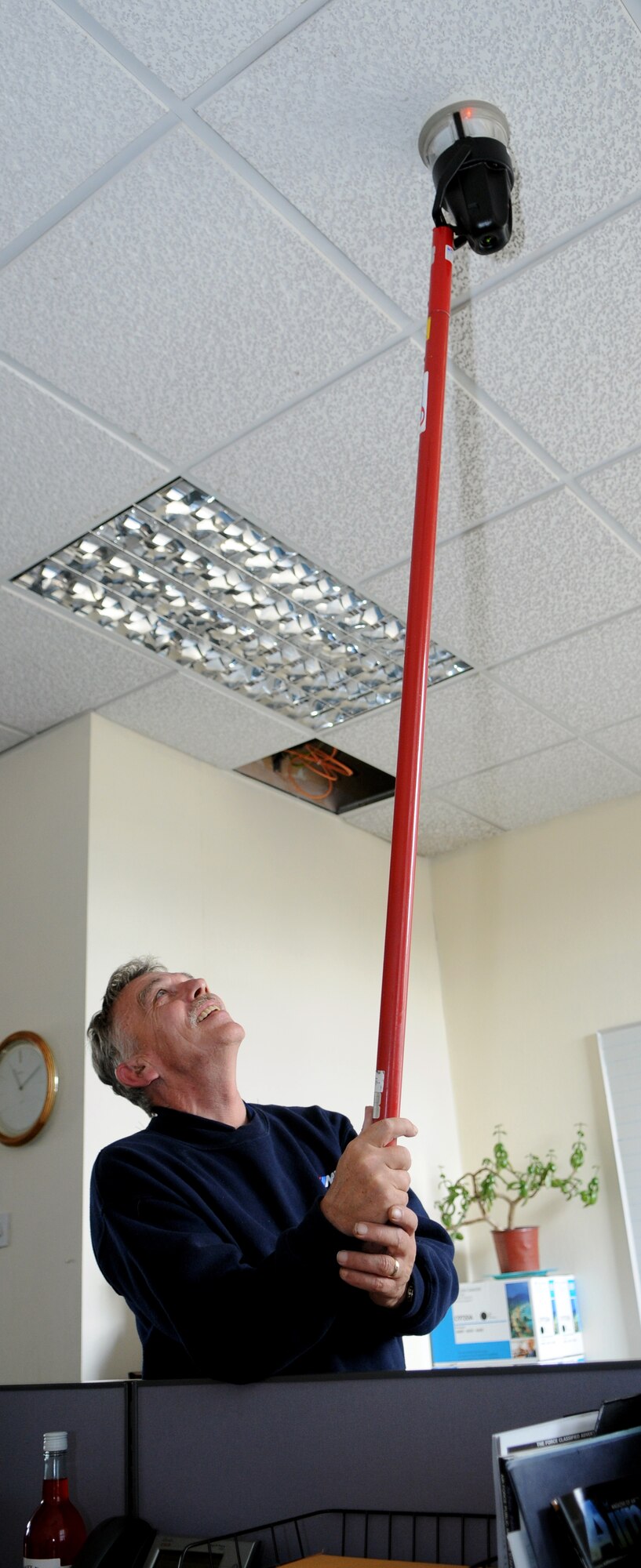 RAF MILDENHALL, England -- Derek Walker, MITIE fire alarm engineer, conducts a routine inspection of fire alarms in the 100th Air Refueling Wing headquarters building Aug. 11.  The aparatus he uses subjects the detector to heat until a light illuminates, indicating a working detector.  (U.S. Air Force photo by Staff Sgt. Austin M. May)
