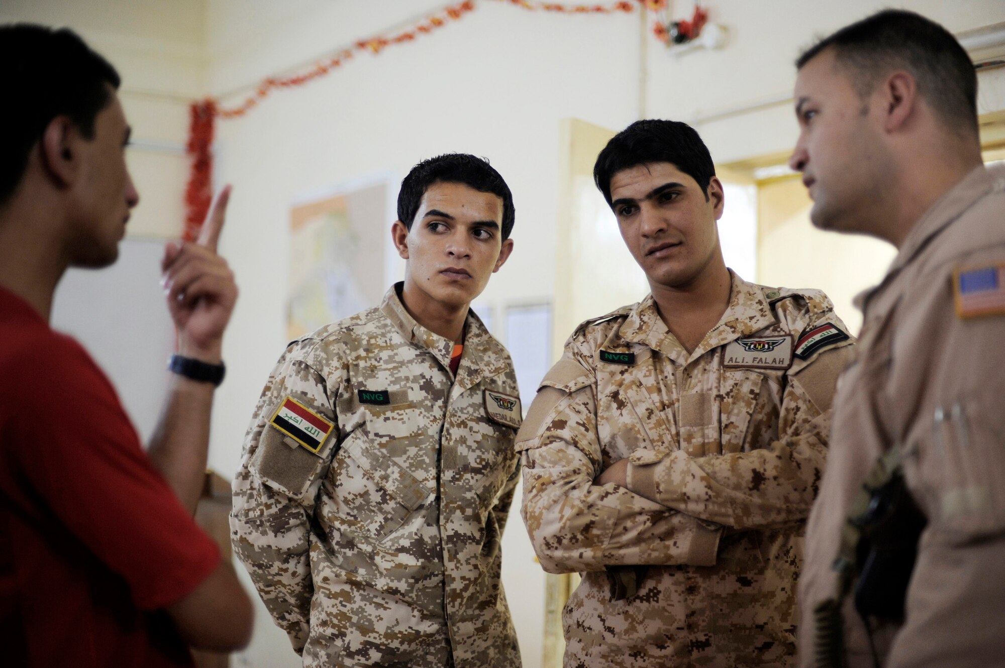 Tech. Sgt. Onnez Rodriquez-Massas (far right) speaks through an interpreter to two Iraqi air force aerial gunners prior to a night mission July 12 at Camp Taji, Iraq. Sergeant Rodriguez-Massas is an aerial gunner assigned to the 721st Air Expeditionary Advisor Squadron and is deployed from Andrews Air Force Base, Md. (U.S. Air Force photo/Staff Sgt. Michael B. Keller)