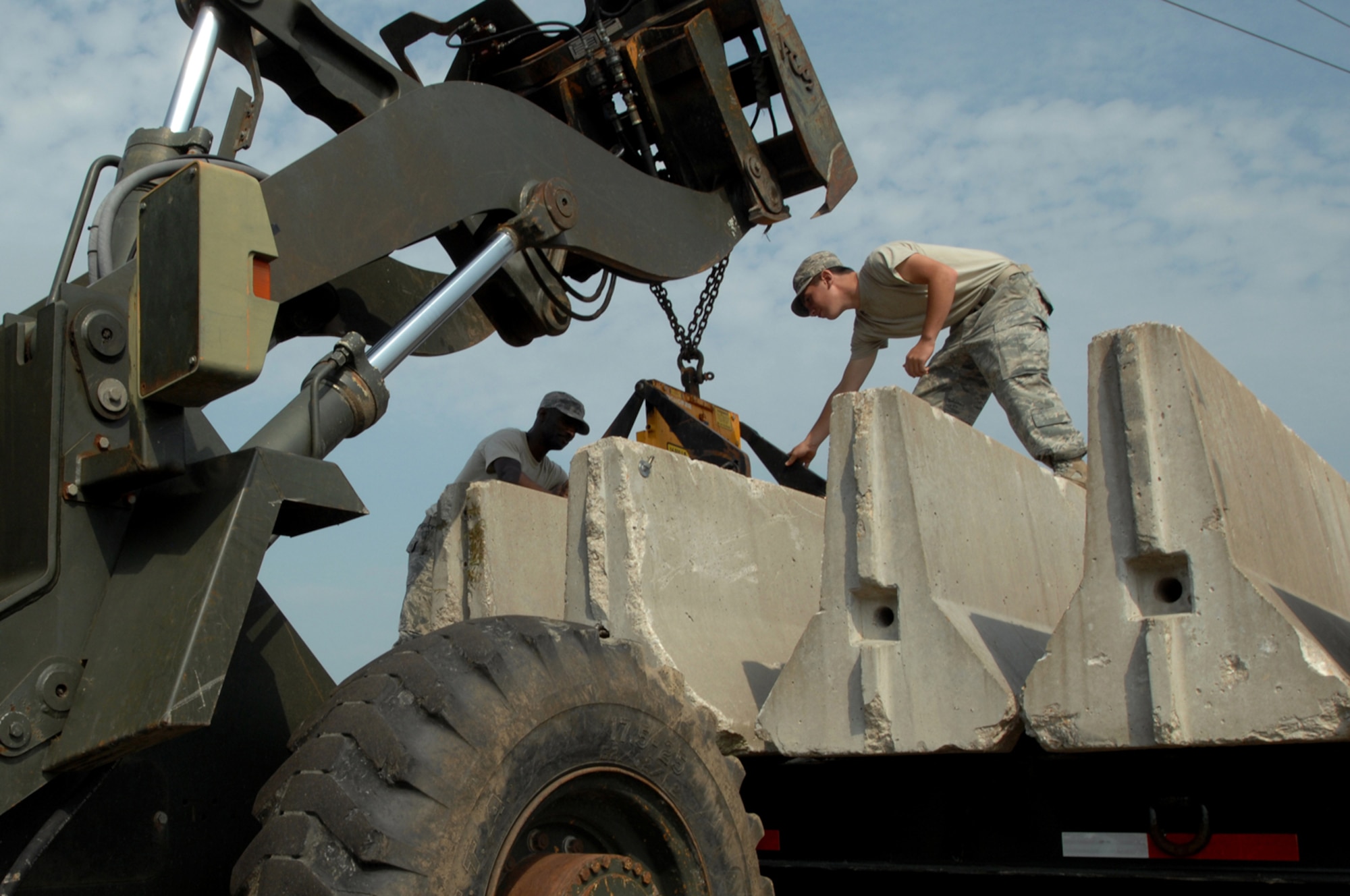 WHITEMAN AIR FORCE BASE, Mo. -  Senior Airman Adam Morrison, (left) and  Airman Logan Thomas, 509th Civil Engineer Squadron, attach a fork lift to a concrete barrier, Aug. 5. The barriers were placed around the 509th Bomb Wing Headquarters building as a part of a force protection scenario during a weeklong Nuclear Operational Readiness Exercise.  (U.S. Air Force photo/Senior Airman Kenny Holston)