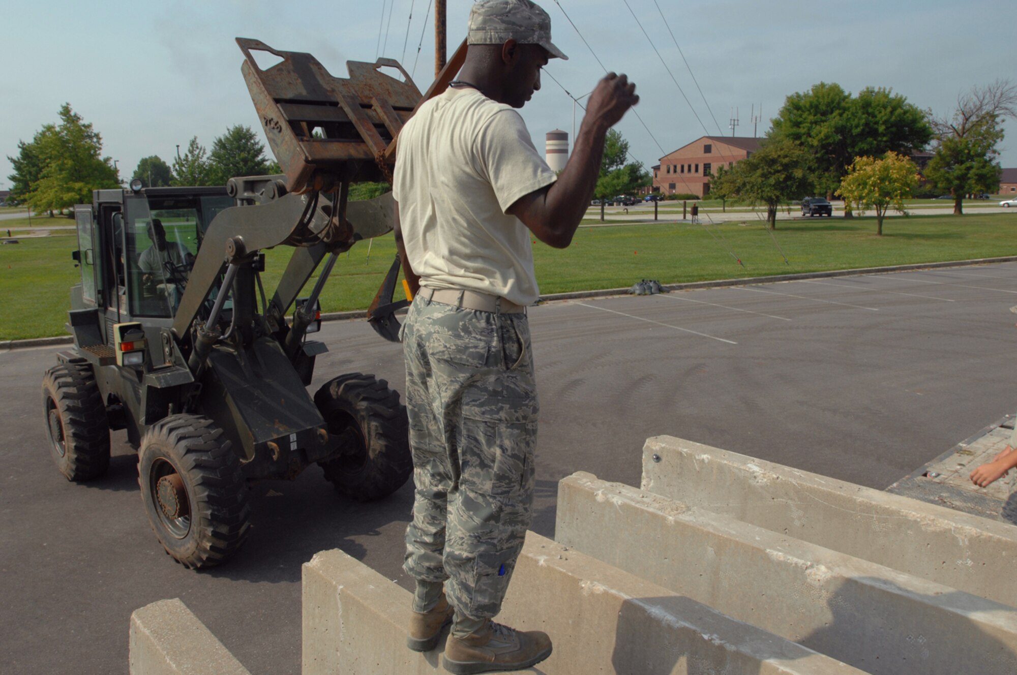 WHITEMAN AIR FORCE BASE, Mo. - Senior Airman Adam Morrison, 509th Civil Engineer Squadron, guides a fork lift into position to unload concrete barriers from a truck, Aug. 5. The barriers were placed around the 509th Bomb Wing Headquarters building as a part of a force protection scenario during a weeklong Nuclear Operational Readiness Exercise. (U.S. Air Force photo/Senior Airman Kenny Holston)