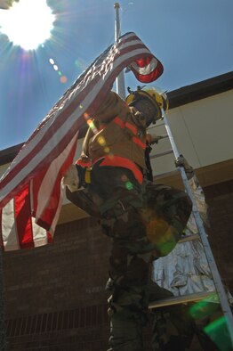 WHITEMAN AIR FORCE BASE, Mo. - Airman 1st Class Walter Daniels, 509th Civil Engineer Squadron Fire Fighter, assists base operations in lowering the flag after I had gotten stuck, July 24. (U.S. Air Force photo/ Senior Airman Kenny Holston))