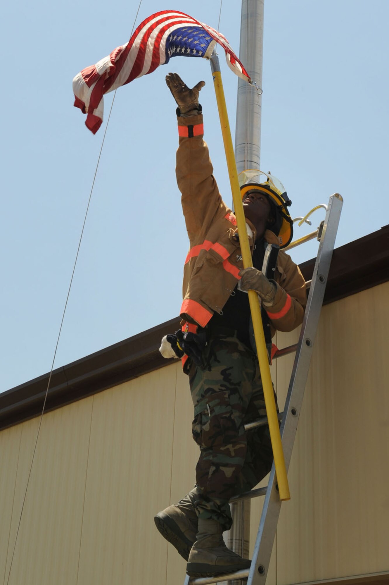 WHITEMAN AIR FORCE BASE, Mo. - Airman 1st Class Walter Daniels, 509th Civil Engineer Squadron Fire Fighter, assists base operations in lowering the flag after it had gotten stuck, July 24. (U.S. Air Force photo/Senior Airman Jason Huddleston)