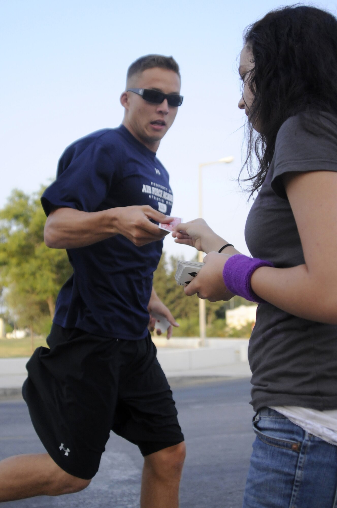 Volunteer Kayleigh Pears, daughter of Col. Andrew Pears, the 39th Mission Support Group commander, hands off a poker card to Airman 1st Class Danny Hagglund, 728th Air Mobilty Squadron, at Incirlik Air Base, Turkey, during the 5k Poker Run Saturday, Aug. 8, 2009. Participants picked up a single card from five points throughout the run, aiming for the best “poker hand” to win a prize. (U.S. Air Force photo/Airman 1st Class Amber Ashcraft)