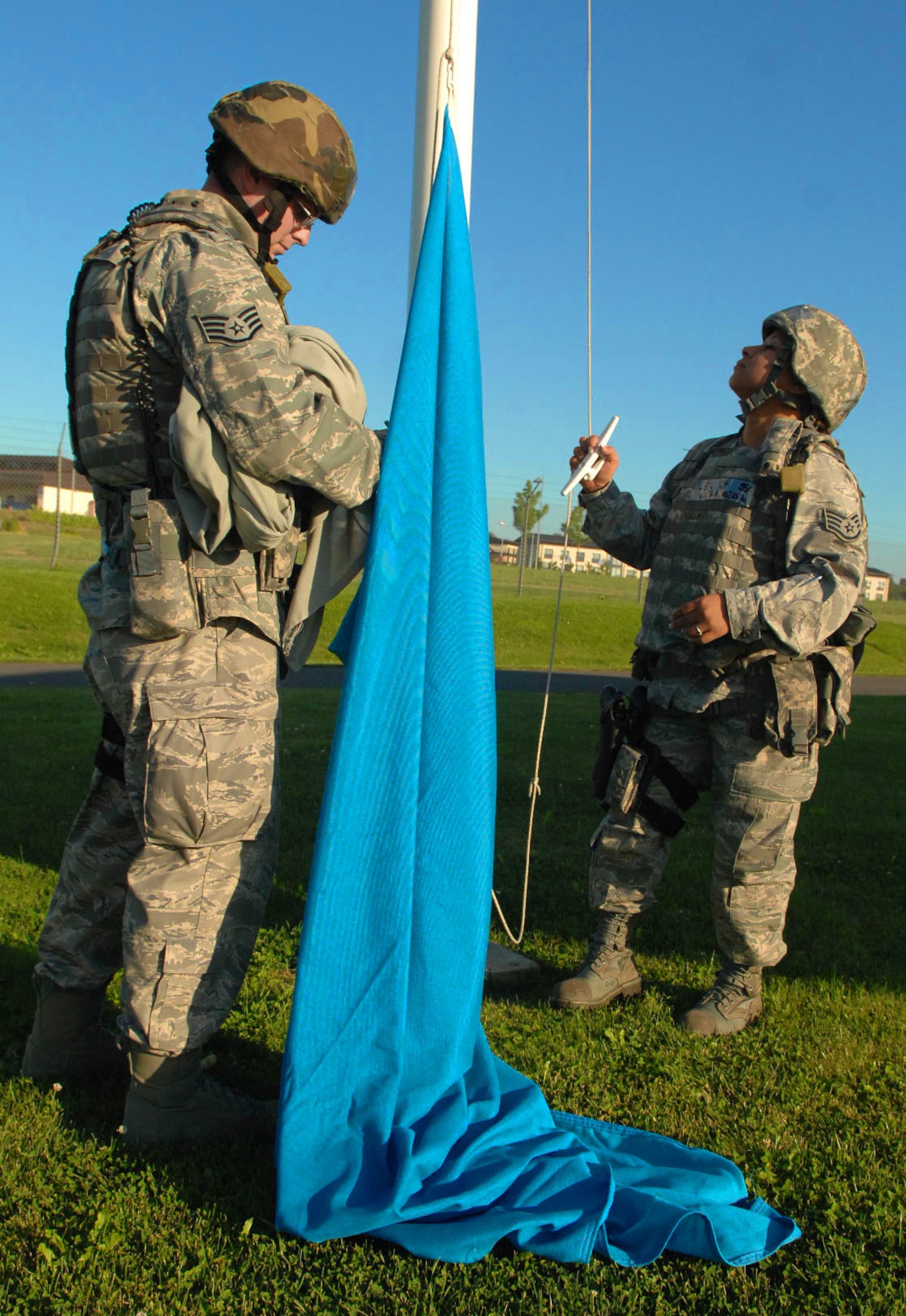 SPANGDAHLEM AIR BASE, Germany -- Staff Sgt. Corina Manzanares and Staff Sgt. Joseph Null, 52nd Security Forces Squadron, prepare to raise a U.S. Air Forces in Europe communication flag at the front gate Aug. 4 during a base-wide exercise in preparation of a NATO Tactical Evaluation scheduled for 2010. USAFE headquarters periodically selects colored flags to be raised as part of a force-protection measure to evaluate base response times. (U.S. Air Force photo/ Airman 1st Class Nick Wilson)