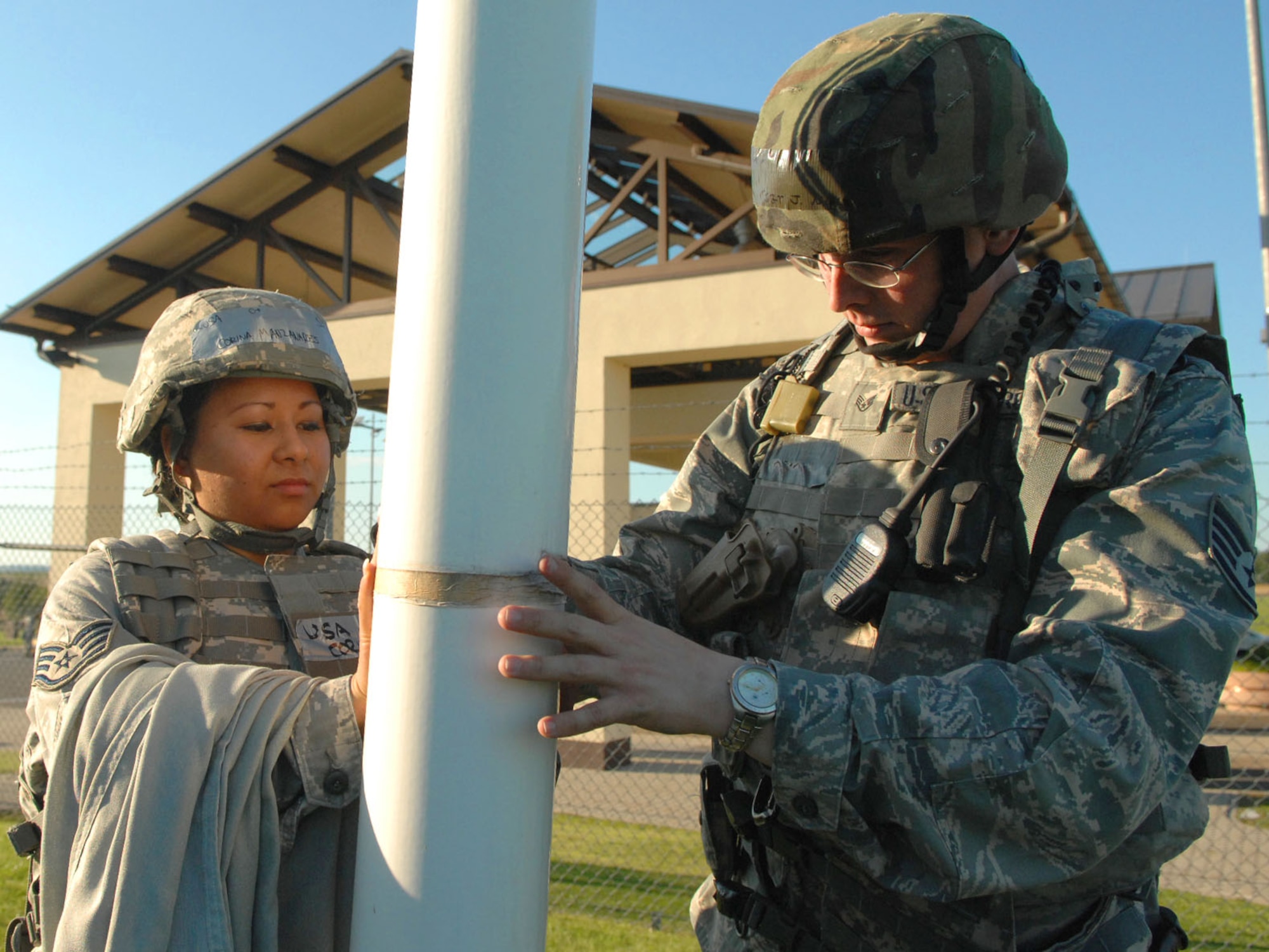 SPANGDAHLEM AIR BASE, Germany -- Staff Sgt. Corina Manzanares and Staff Sgt. Joseph Null, 52nd Security Forces Squadron, tighten the rope of a U.S. Air Forces in Europe communication flag at the front gate Aug. 4 during a base wide exercise in preparation of a NATO Tactical Evaluation scheduled for 2010. USAFE headquarters periodically orders Airmen to raise a colored flag as part of a force protection measure to evaluate base response times. (U.S. Air Force photo/ Airman 1st Class Nick Wilson)