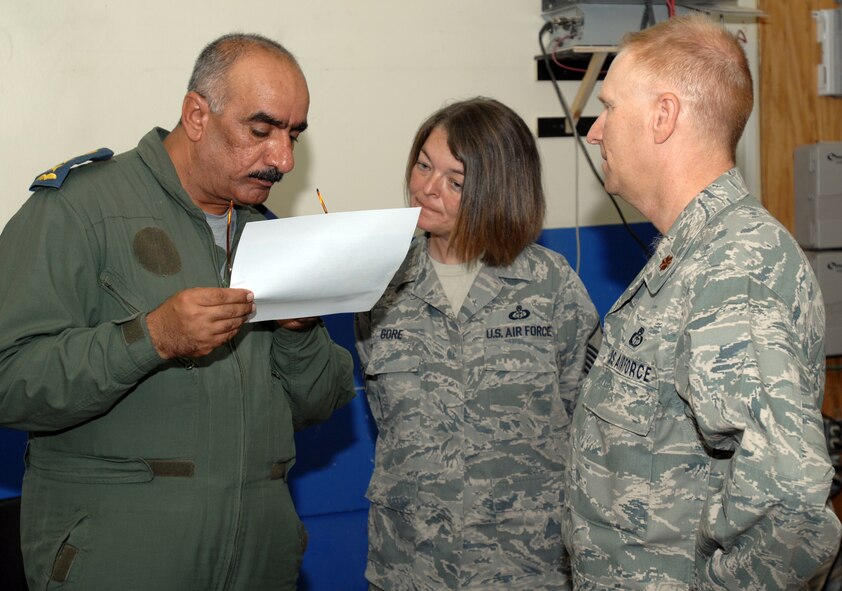 KIRKUK AIR BASE, Iraq -- Col. Salman, Iraq Air Force Weather Service director, goes over a training schedule for IqAF weather officers as Master Sgt. Lisa Gore, 506th Expeditionary Operational Support Squadron weather flight superintendent, and Maj. Barry Hunte, Iraq Training and Advisory Mission-Air Forces' weather advisor, stand by. Recently a new partnership was established between the 506th EOSS weather flight and the IqAF weather team here that will improve the services they provide.