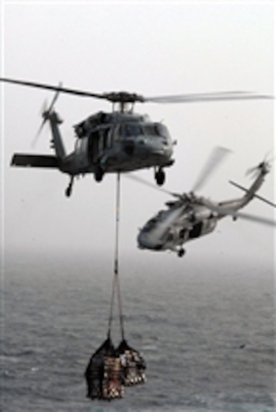 Two MH-60S Knighthawk helicopters from Helicopter Sea Combat Squadron 21 transfer cargo from the fast-combat support ship USNS Rainier (T-AOE 7) to the aircraft carrier USS Ronald Reagan (CVN 76) during a replenishment at sea while underway in the Gulf of Oman on Aug. 7, 2009.  