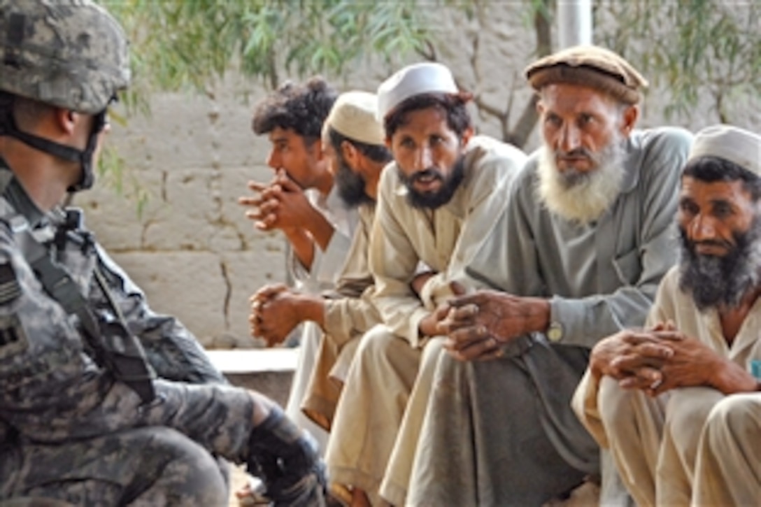 A U.S. Army soldier listens to villagers during a discussion  near Combat Outpost Honaker Miracle, Afghanistan, July 29, 2009. The soldier, assigned to the 2nd Battalion, 12th Infantry Regiment, participated in the meeting with other U.S. and Afghan soldiers.