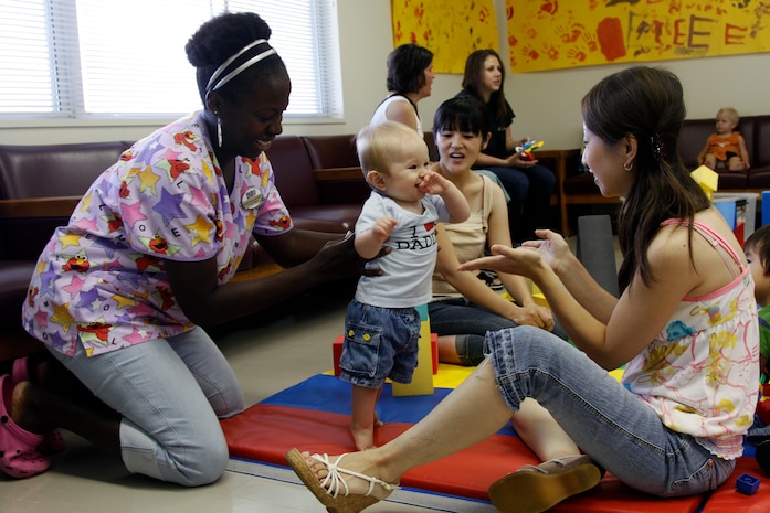 Registered nurse Rafiah Meekins, New Parent Support Group nurse, helps a mother teach her son how to walk during Playmorning in Building 656’s community room here Aug. 11. Playmorning is one of the many services provided by the New Parent Support Group to help station families with children newborn to 5 years of age.